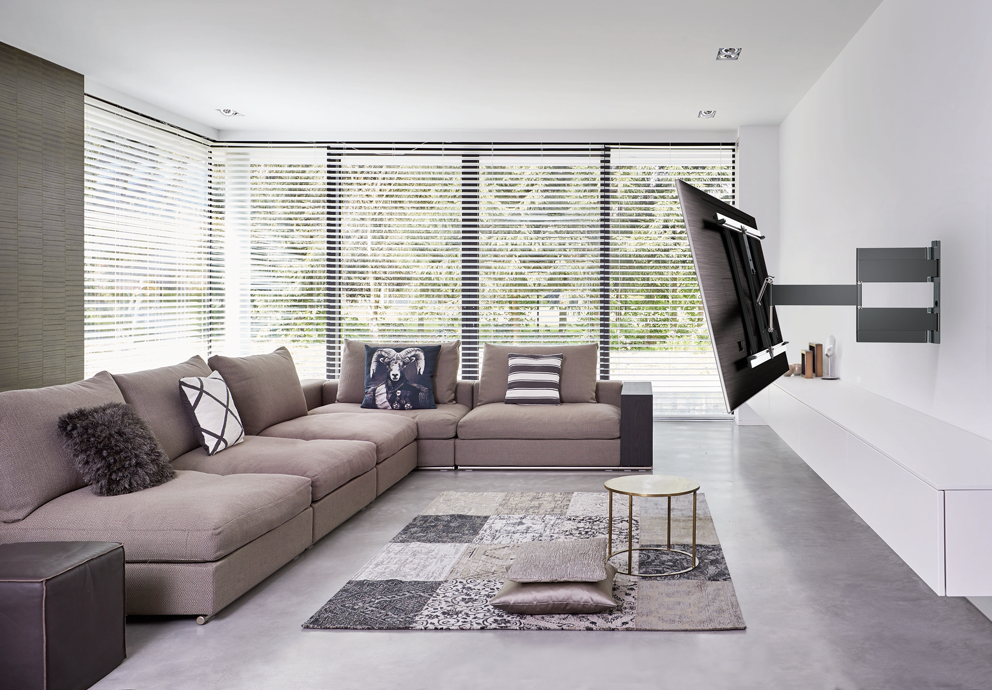 Een moderne woonkamer met een grote hoekbank en een tv aan de muur.