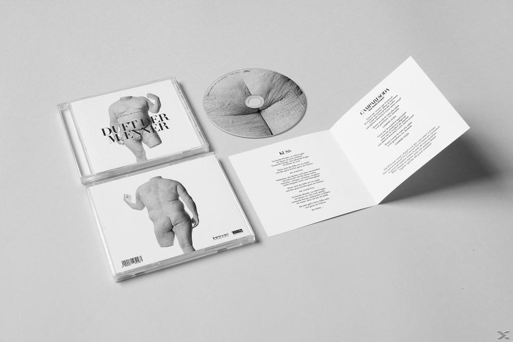 CD-Hüllen mit Kunst, eine CD und ein aufgeklapptes Booklet auf grauem Hintergrund.