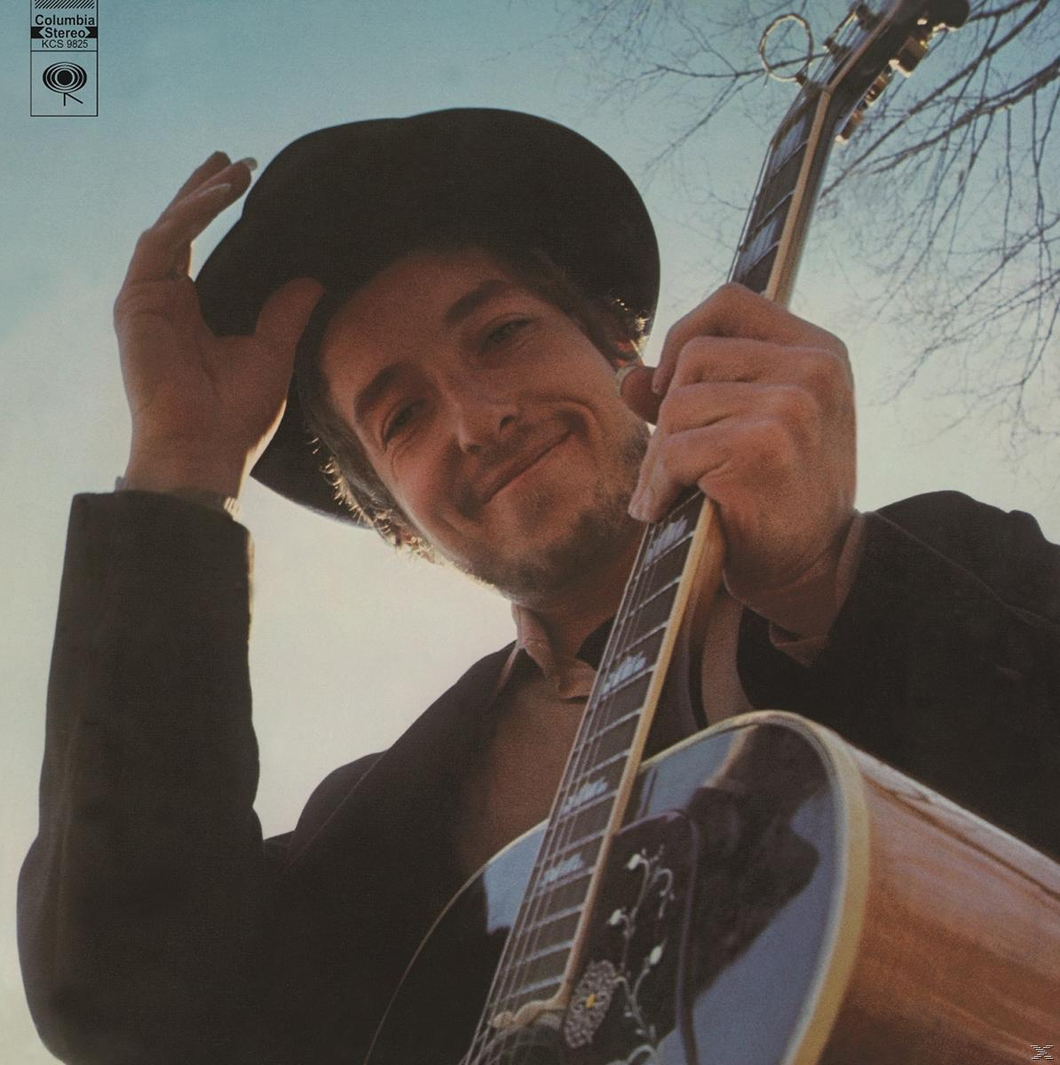 Albumcover. Bob Dylan hält eine Gitarre. Schwarzer Hut, lächelndes Gesicht. Klassischer Look.