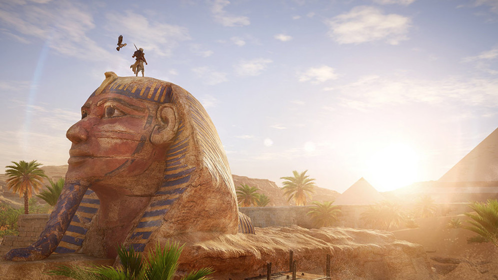 Uitzicht op de Sfinx en een piramide. Een persoon staat op de Sfinx. De lucht is blauw en zonnig.