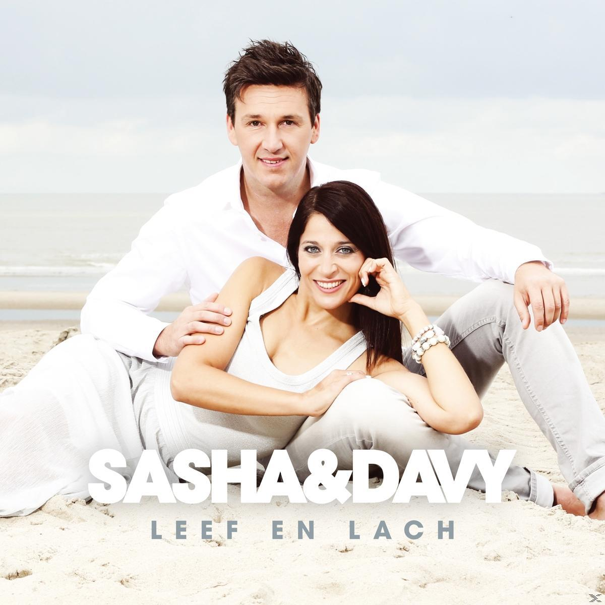 Couple sur la plage, femme en haut blanc, homme en chemise blanche, texte "SASHA & DAVY LEEF EN LACH".