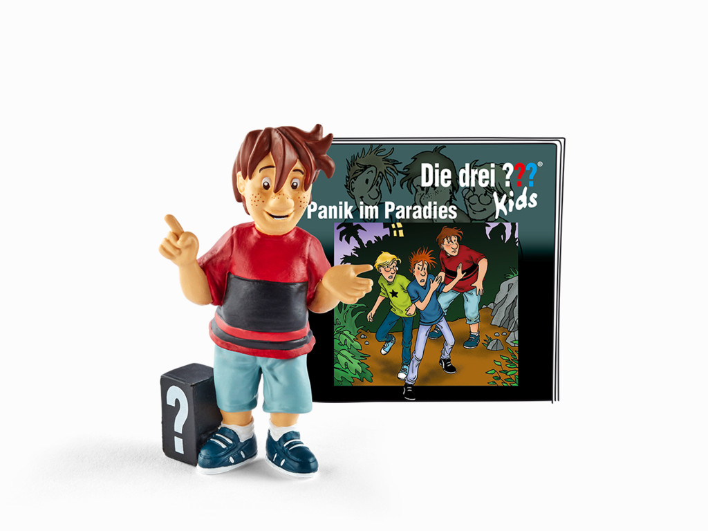 Eine Figur eines Jungen zeigt auf ein Buchcover mit dem Titel 'Die drei ??? Kids'. Das Cover zeigt drei Kinder in einer Dschungelszene.