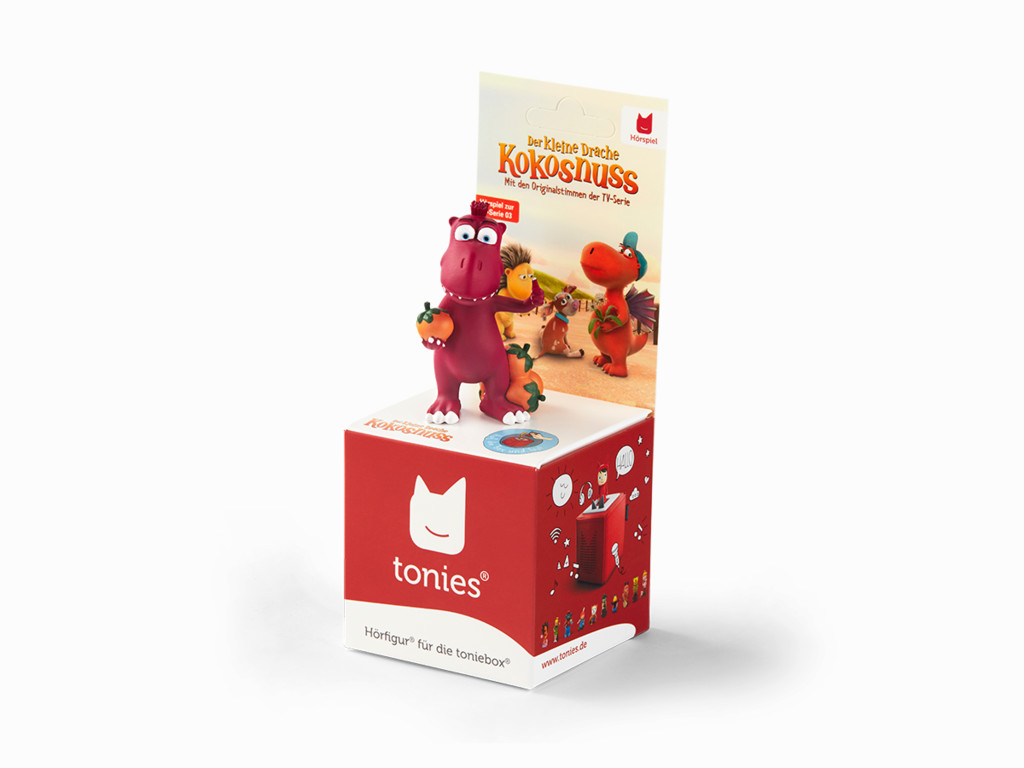 Eine rote und weiße Tonies-Box mit einer Cartoon-Drachenfigur oben drauf. Tonies-Logo.