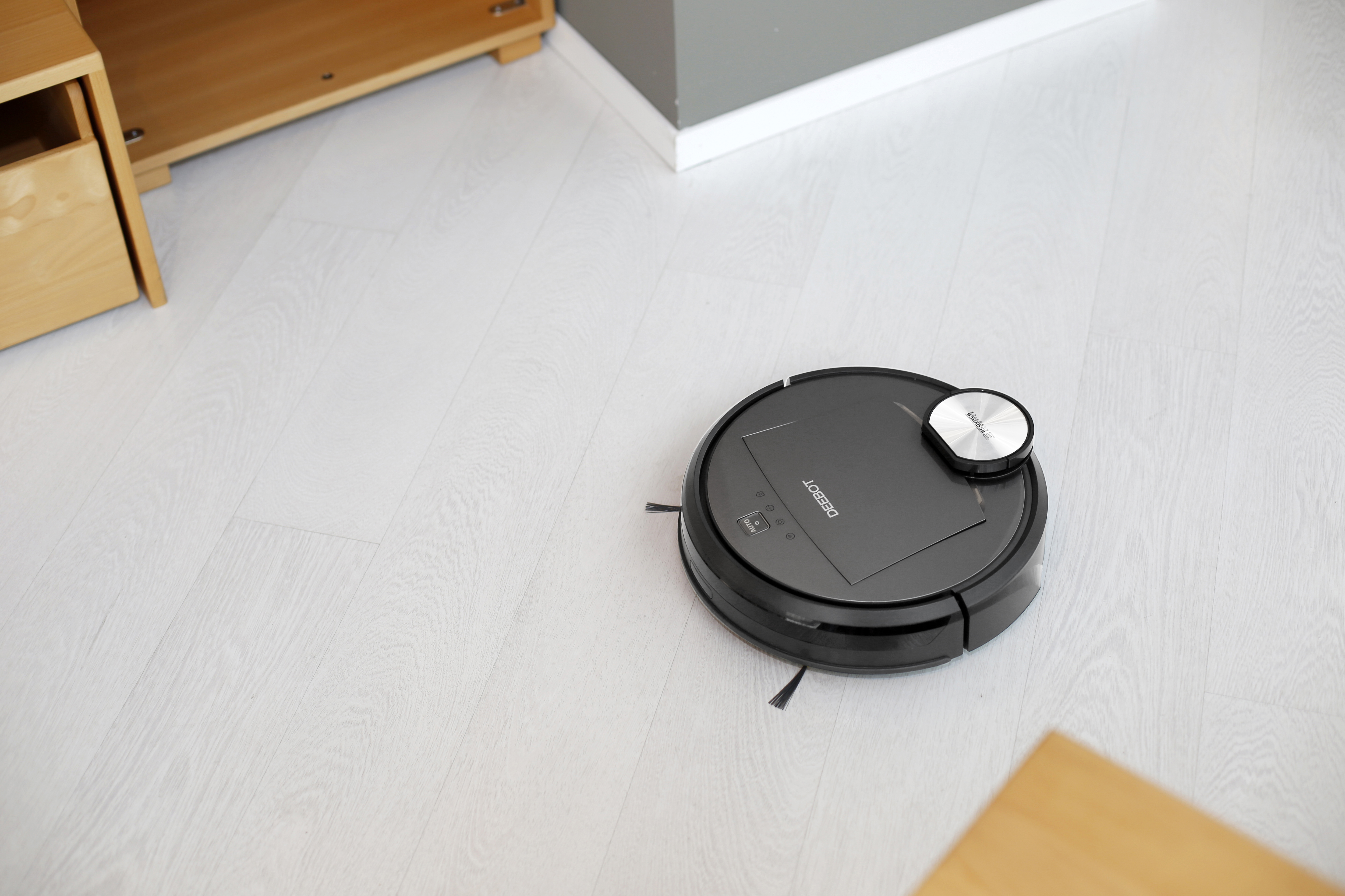 DEEBOT Roboter-Staubsauger auf Holzboden, in der Nähe von Möbeln.