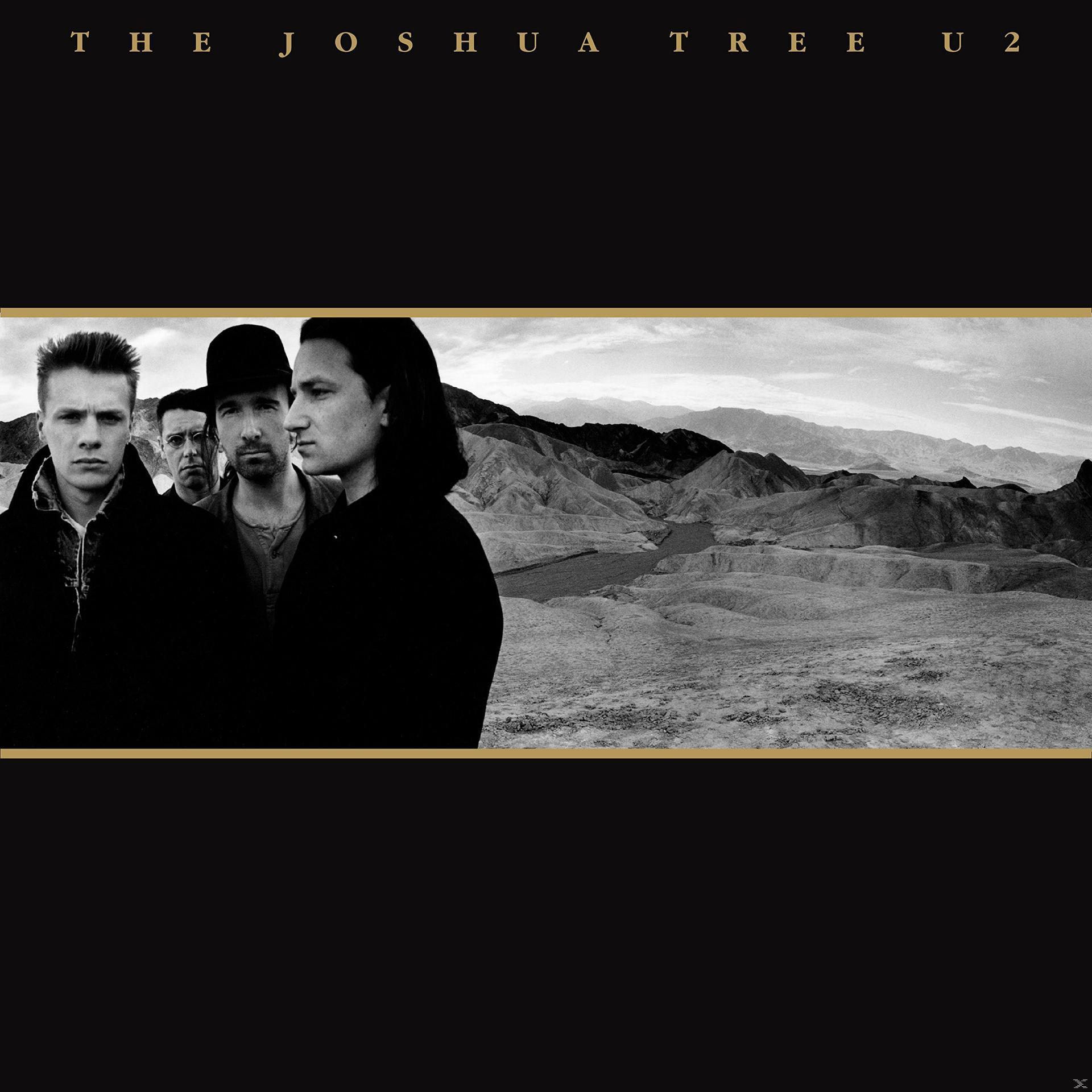 Albumcover: U2-Bandmitglieder in Schwarzweiß vor einer Wüstenlandschaft. Text 'THE JOSHUA TREE U2' oben.