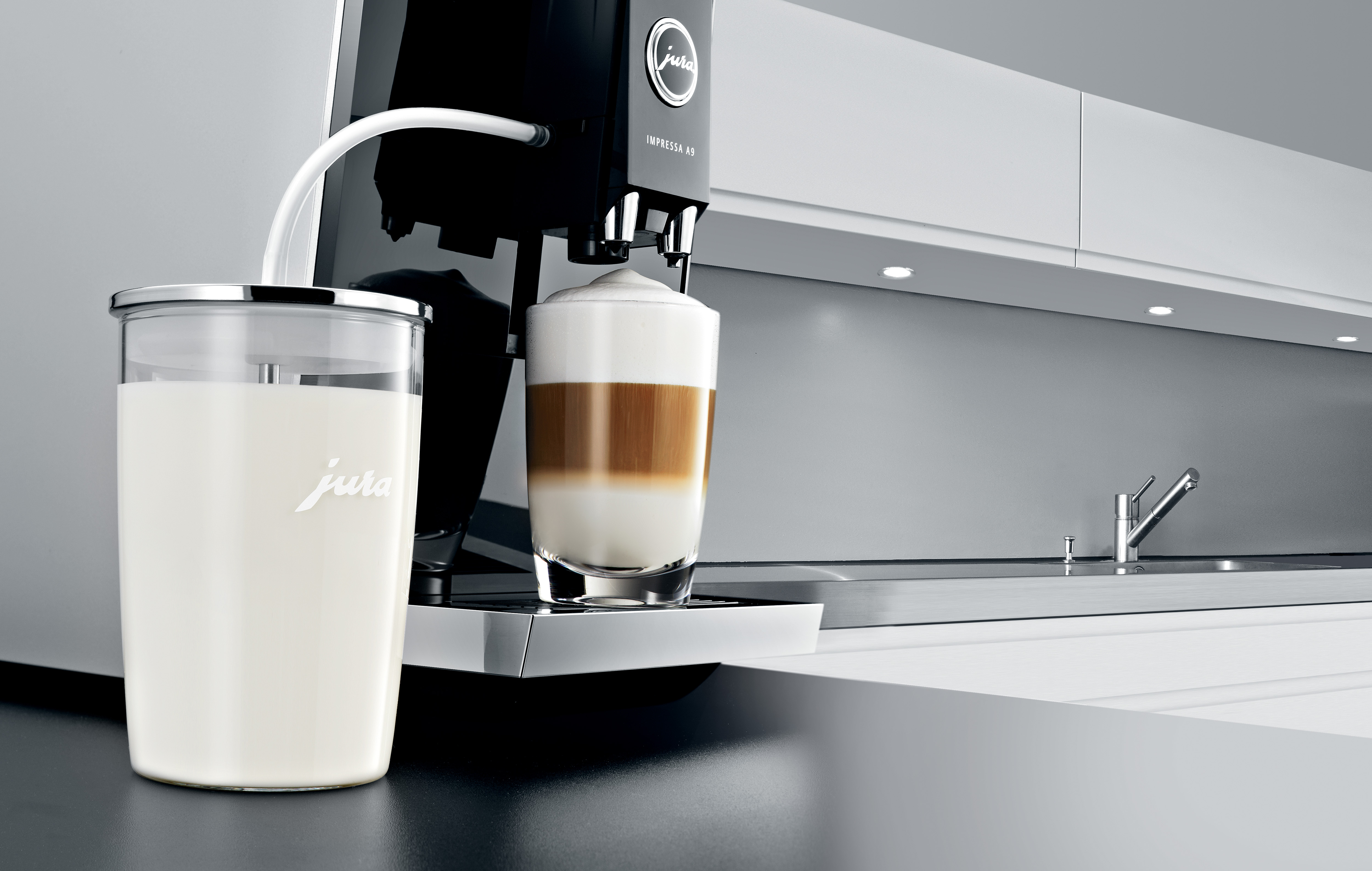 Coffee machine with milk container. Latte in a glass. White kitchen background.