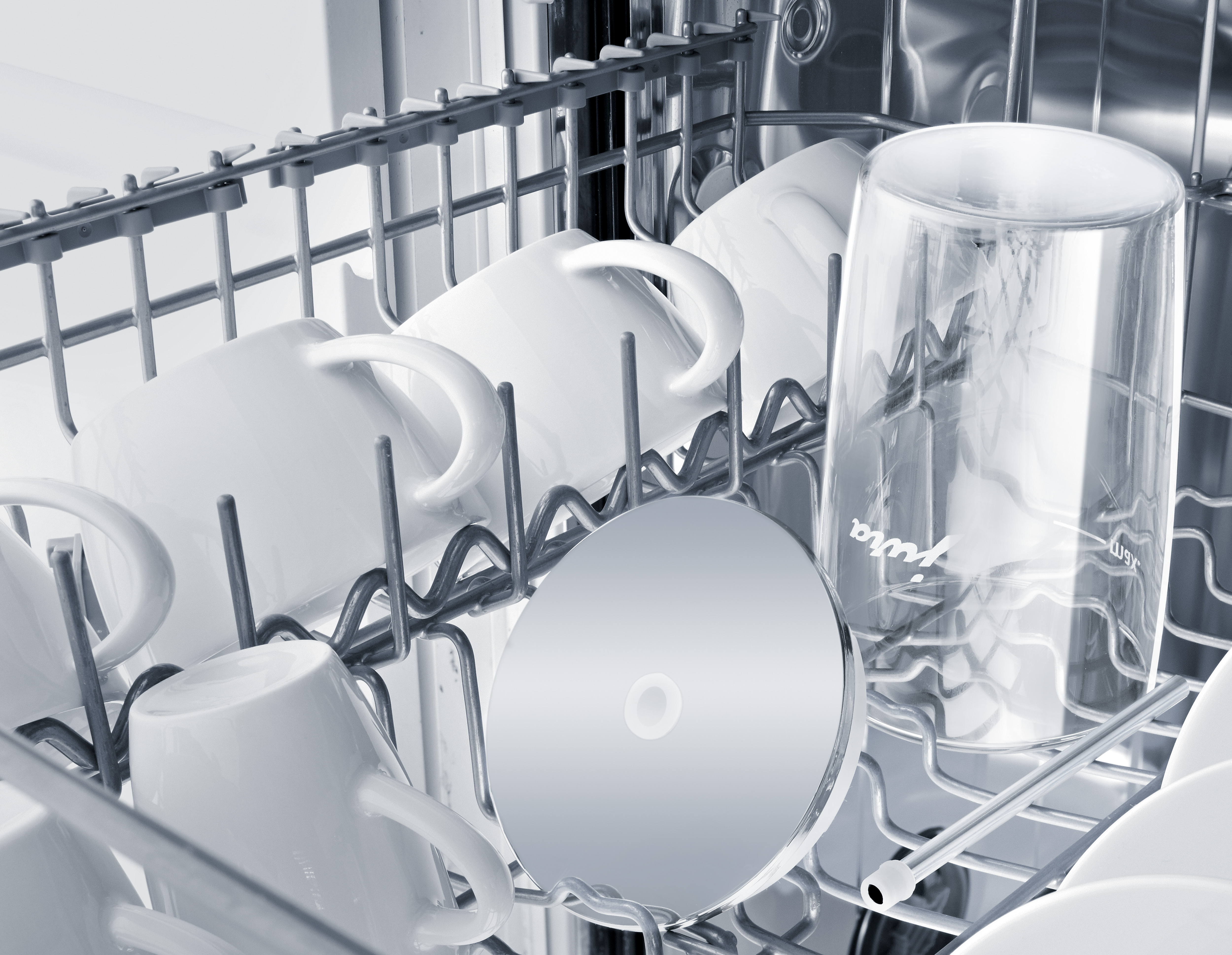 Dishwasher interior with white mugs, a glass, and a CD in a metal rack.