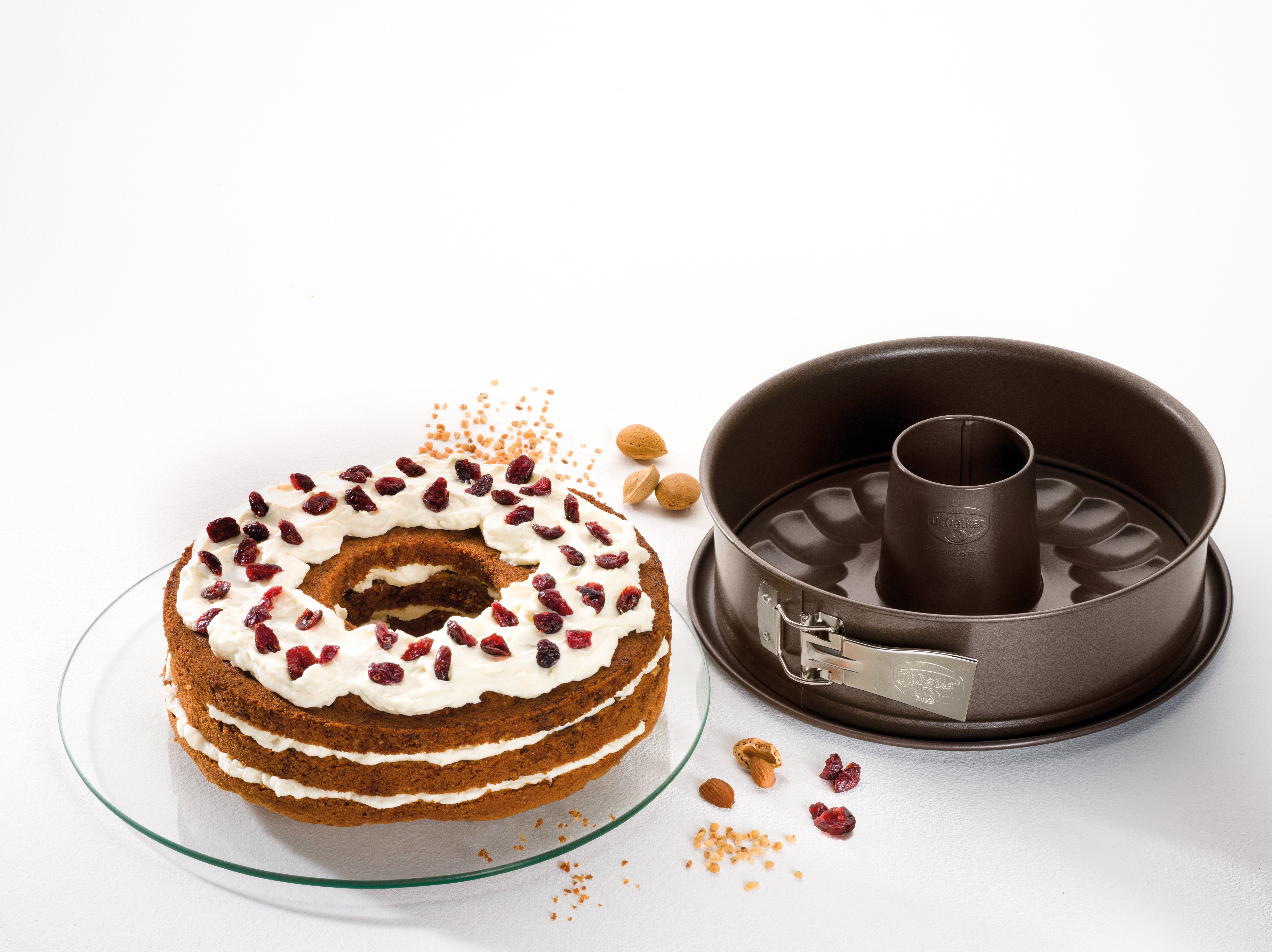 Geschichteter Kuchen mit weißem Zuckerguss, Cranberries und Gugelhupf.