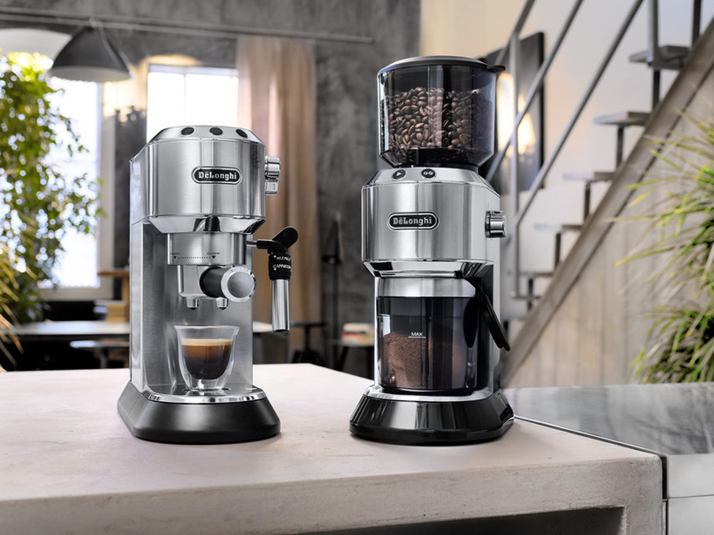 Two silver and black espresso machines and grinders are shown on a white countertop in a kitchen setting.