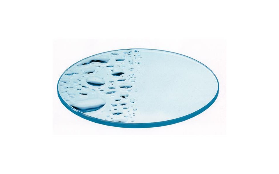 A circular piece of glass with water droplets on the left side and clean on the right.