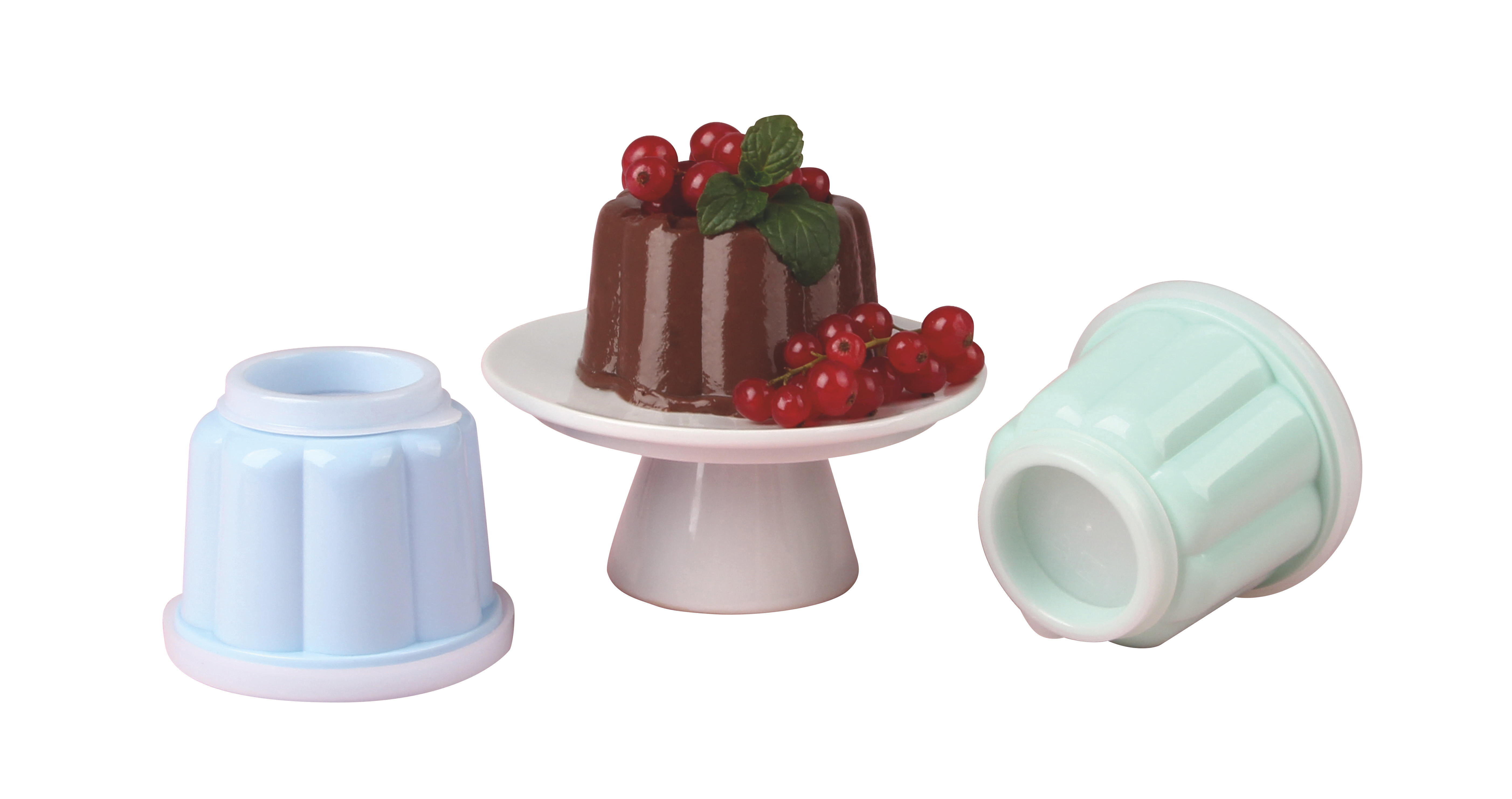 Schokoladenpuddingkuchen auf weißem Ständer, rote Johannisbeeren und blaue und grüne Formen auf weißem Hintergrund.