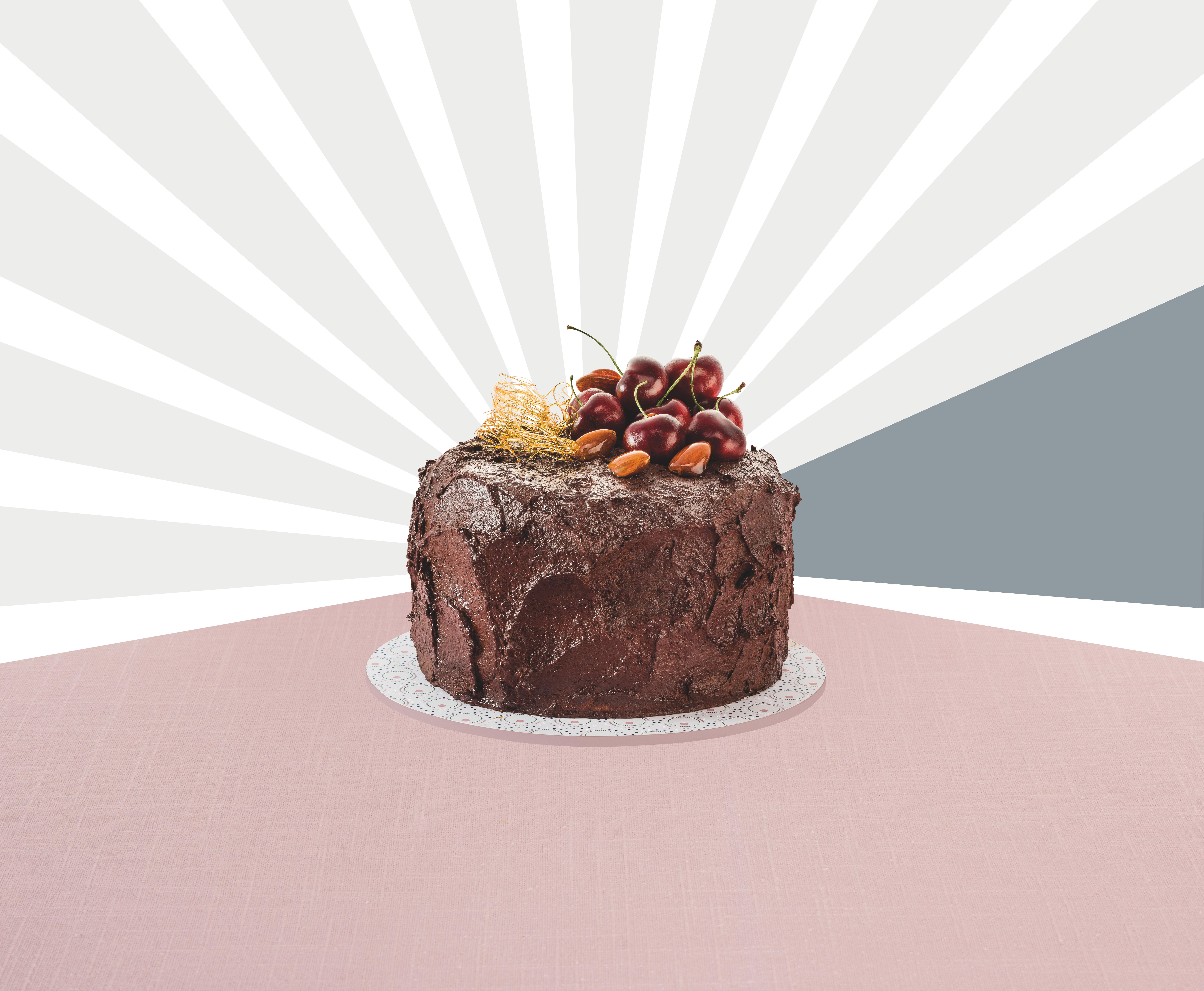 Schokoladenkuchen mit Kirschen und Mandeln auf einem weißen Teller, vor pink-weißem Hintergrund.