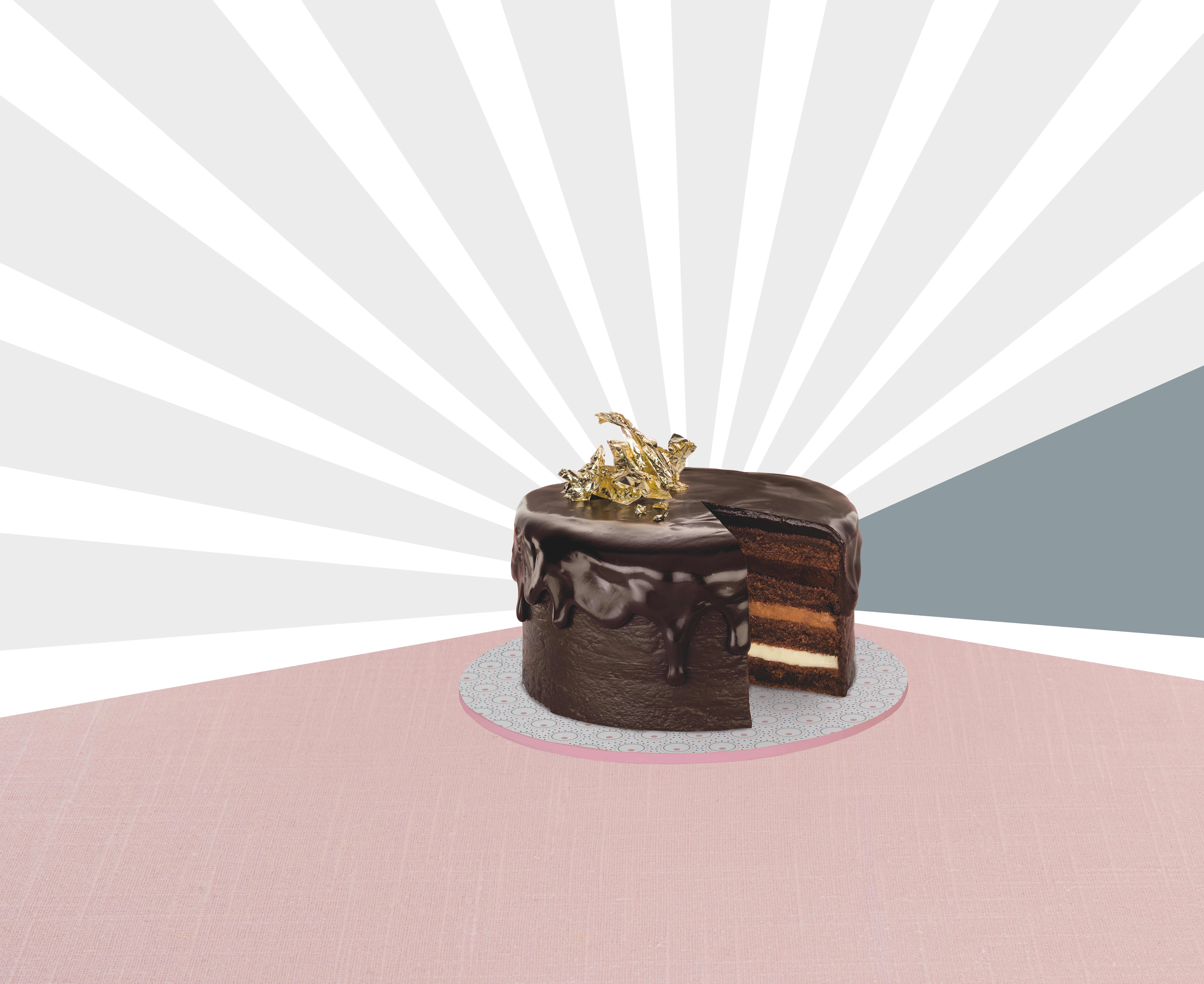 Schokoladenkuchen mit einem entfernten Stück, mit Blattgold verziert, auf weißem und rosa Hintergrund.