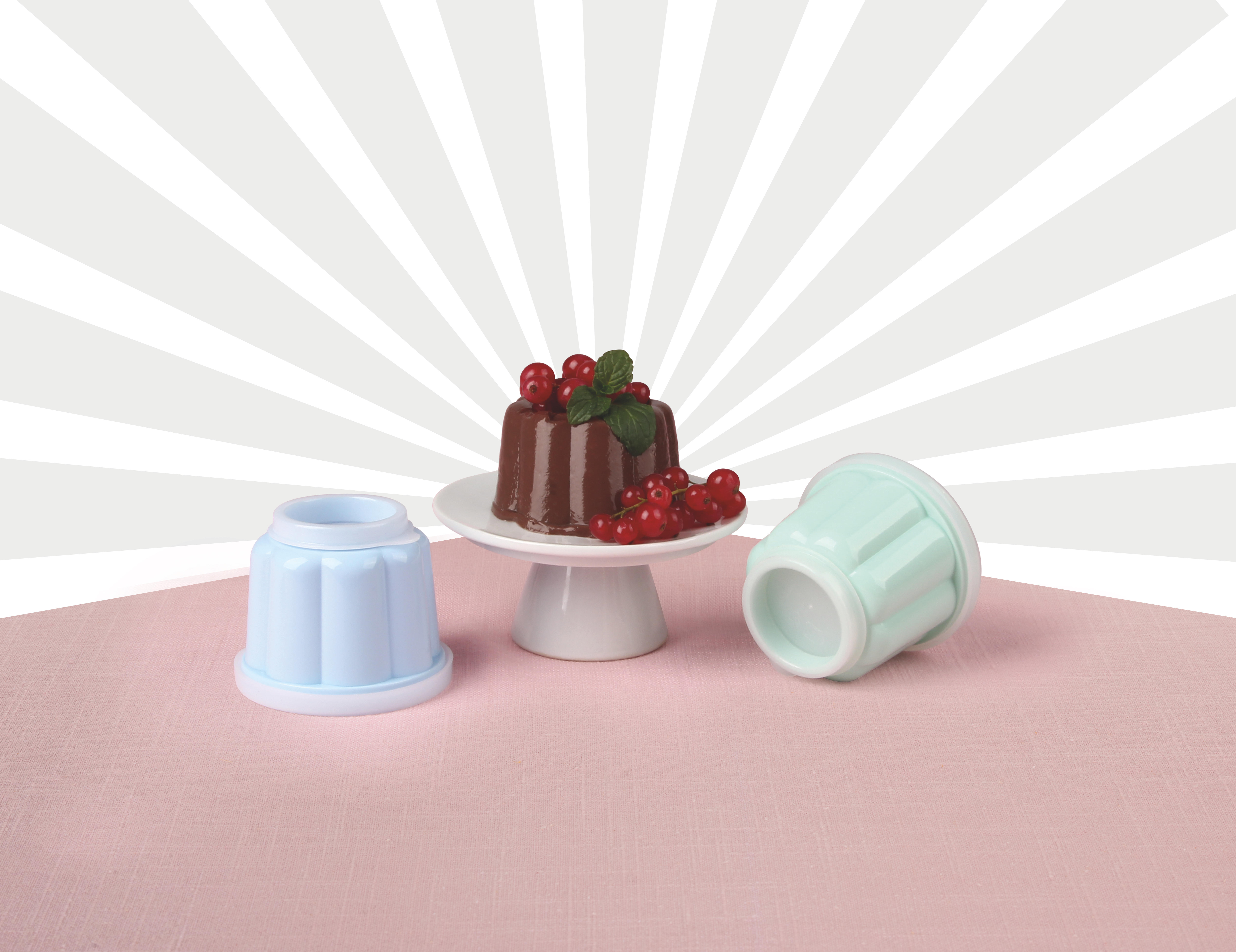 Schokoladenpudding auf weißem Ständer, mit Beeren. Zwei leere blaue Formen.