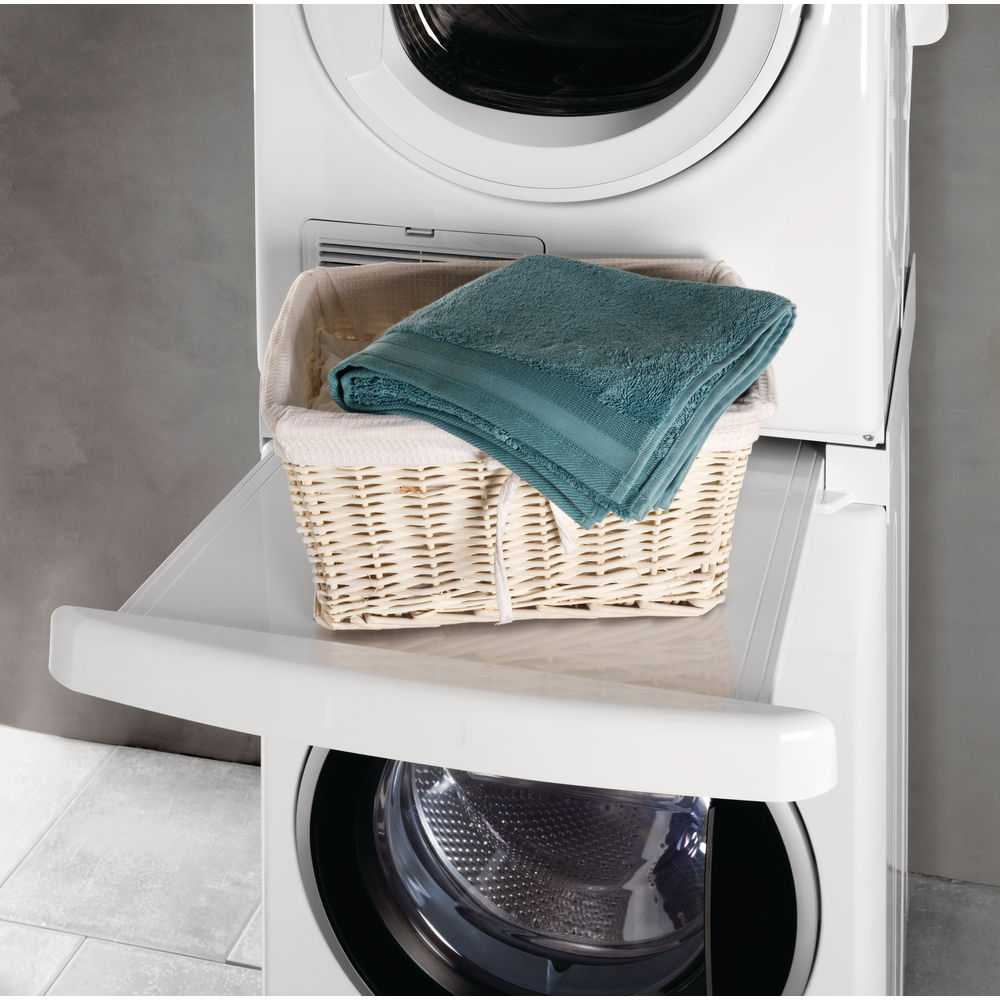 Lave-linge blanc avec un panier de serviettes dessus. Un tiroir blanc est ouvert.