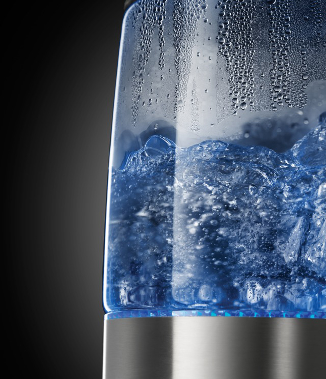 Nahaufnahme eines elektrischen Glaskessels mit kochendem Wasser, blaues Licht am Boden.