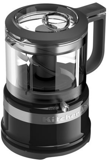 Robot culinaire noir et argent. Il a un bol en plastique transparent et une poignée. KitchenAid est visible.