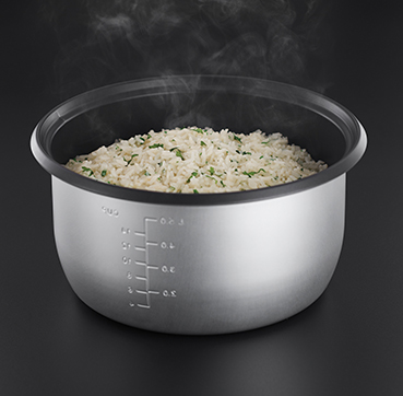 Rice cooker with cooked rice and steam rising. Black background.