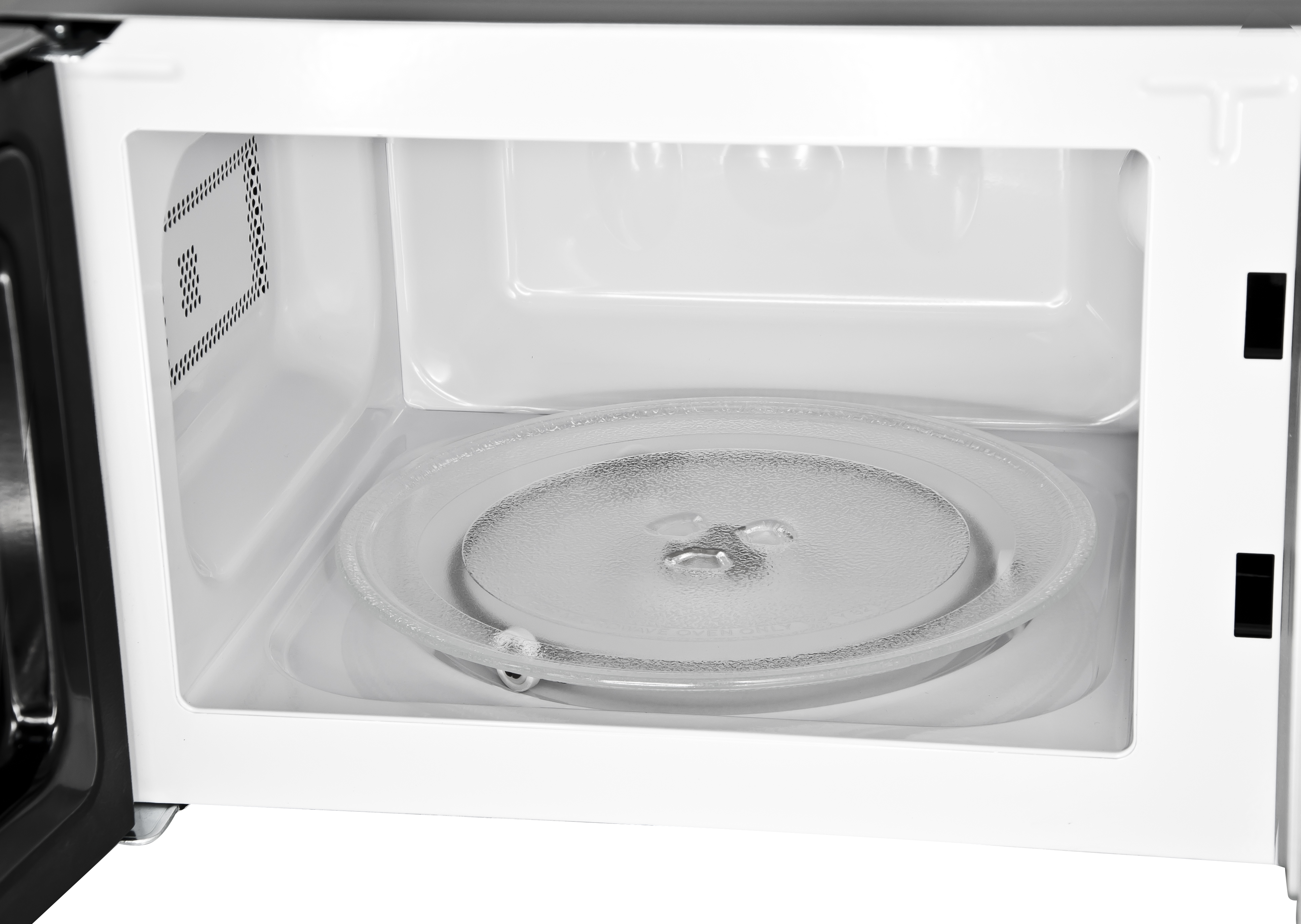 Das Innere einer weißen Mikrowelle. Eine Glasplatte befindet sich in der Mitte. Der Innenraum ist sauber und gut beleuchtet.