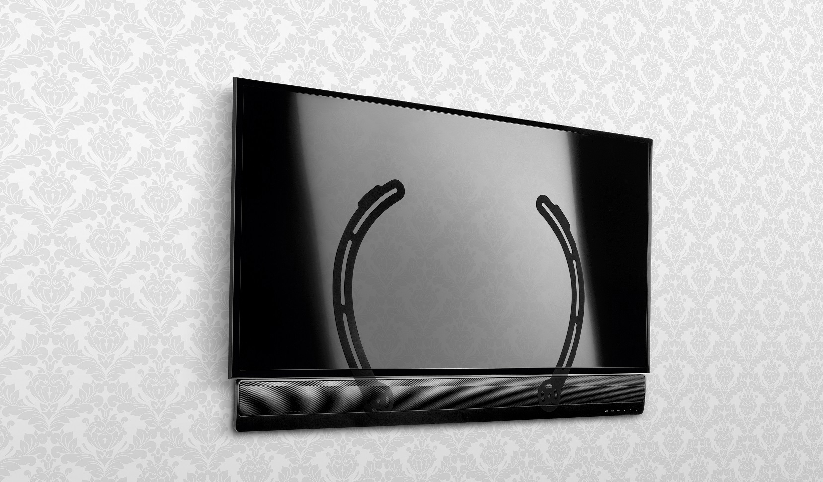 Ein schwarzer Fernseher mit Soundbar an der Wand. Die Tapete hat ein Blumenmuster. Der Fernseher ist montiert.
