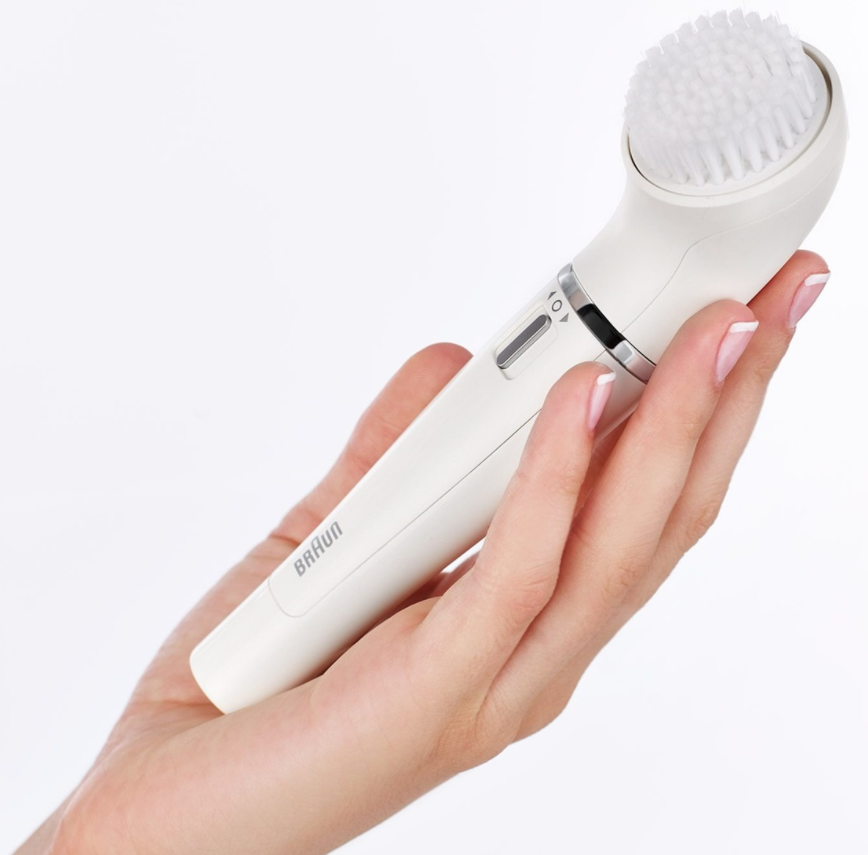 Une main tenant une brosse nettoyante pour le visage Braun blanche, montrant la tête et le panneau de contrôle.