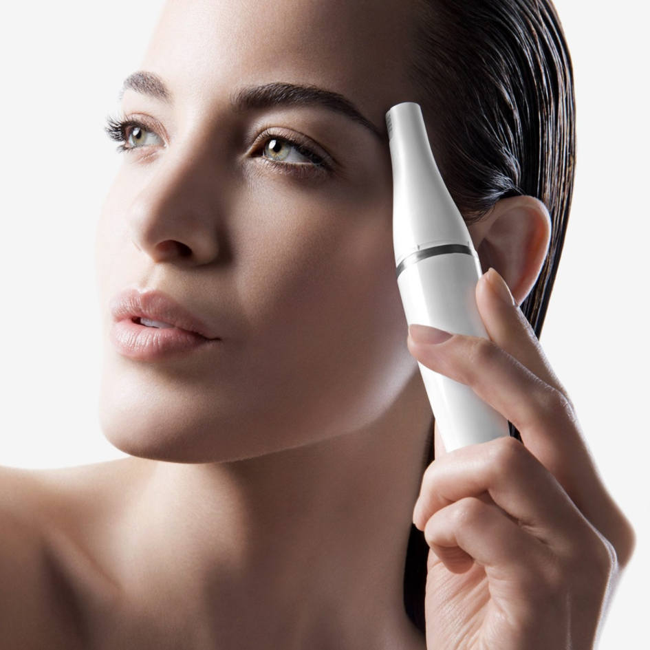 Femme avec un appareil blanc près de son œil. Elle regarde vers le haut avec une expression neutre.