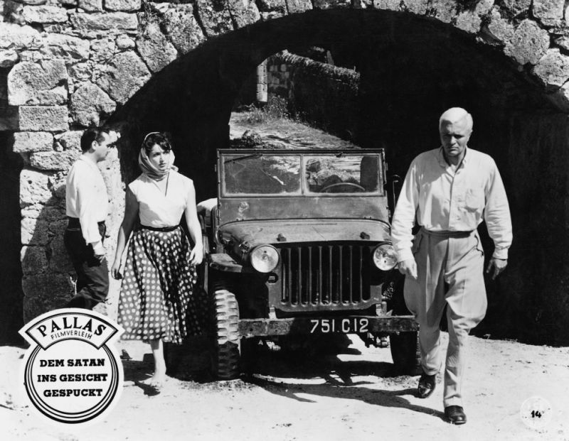 S/W-Bild: Personen in der Nähe eines Jeeps unter einem Torbogen.