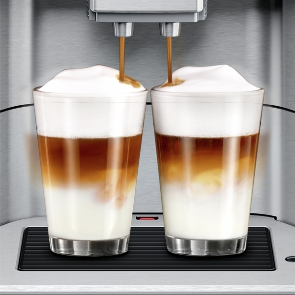 Zwei Gläser mit geschichtetem Kaffee und Schaum, die von einer Maschine ausgegeben werden.