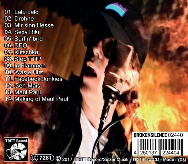 Ein Mann singt in ein Mikrofon auf einer Bühne, mit einer Titelliste.