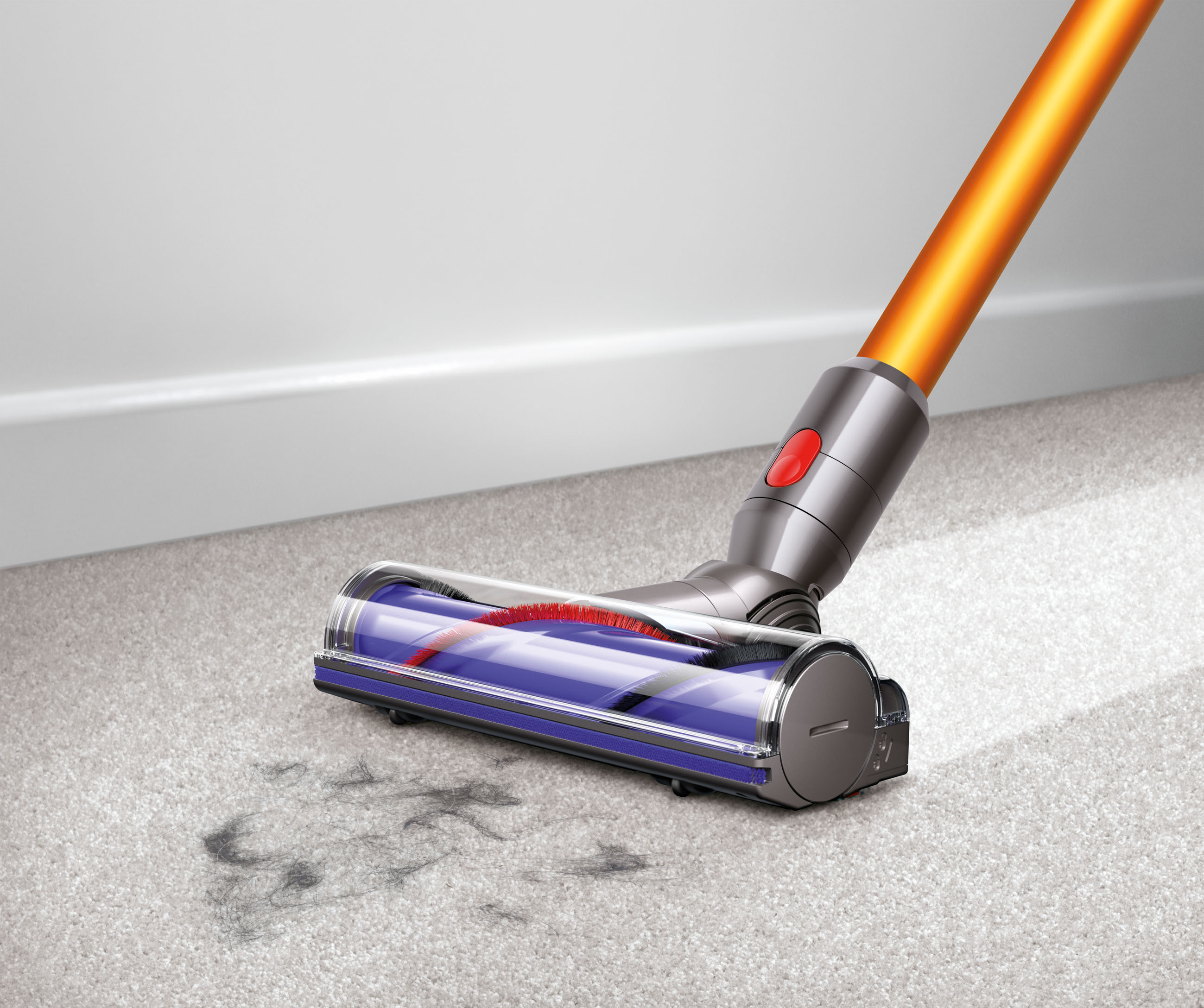Dyson-Staubsauger reinigt einen Teppich, orangefarbener Griff und silberner Kopf, Schmutz zeigend.