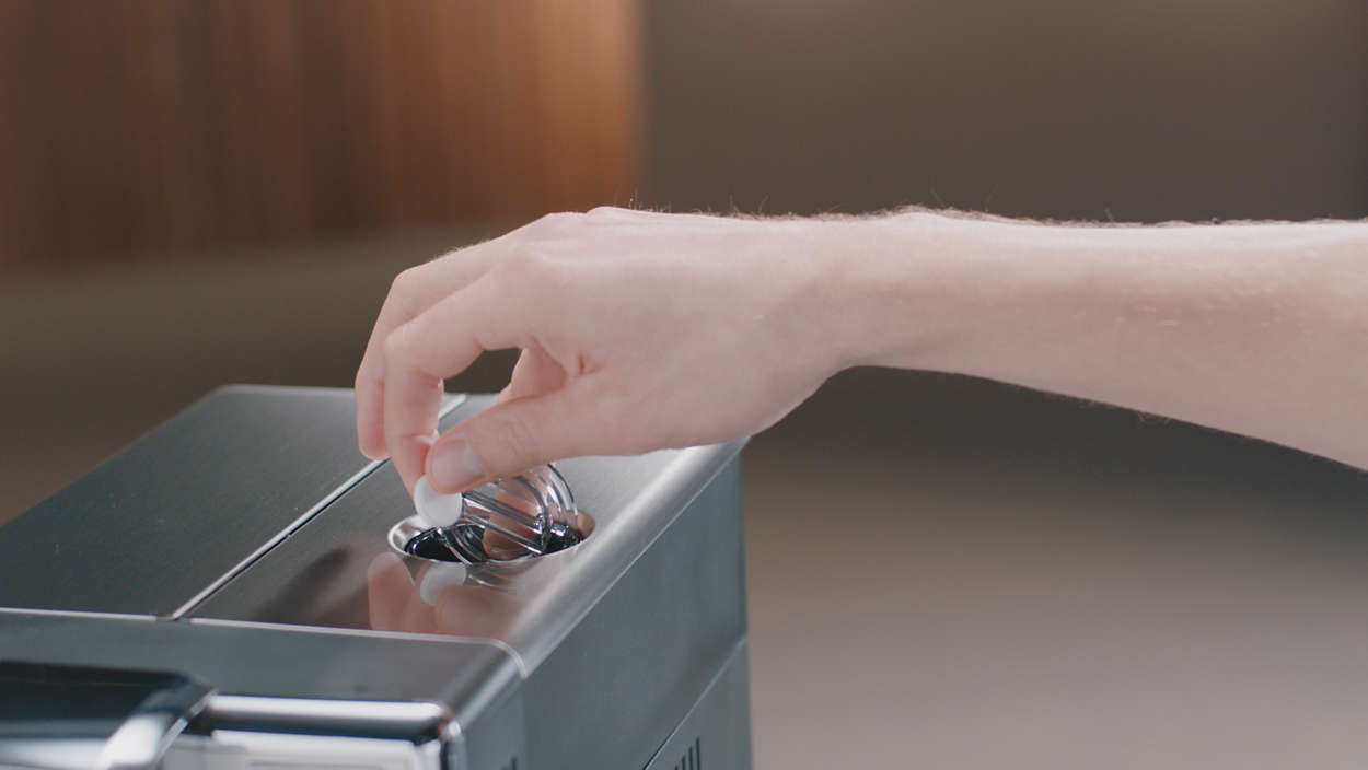 A hand is putting a white object into a black and silver machine.