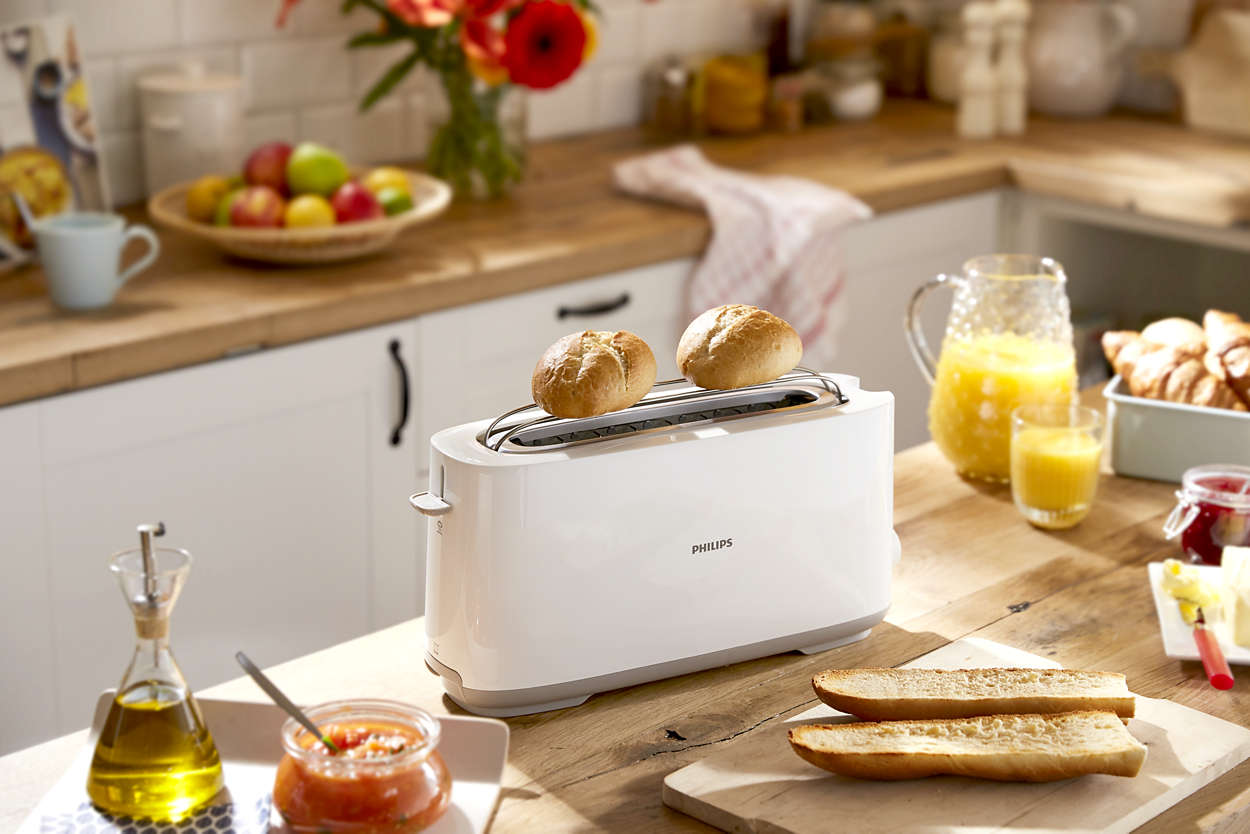 White toaster with toast and other breakfast items on the table.