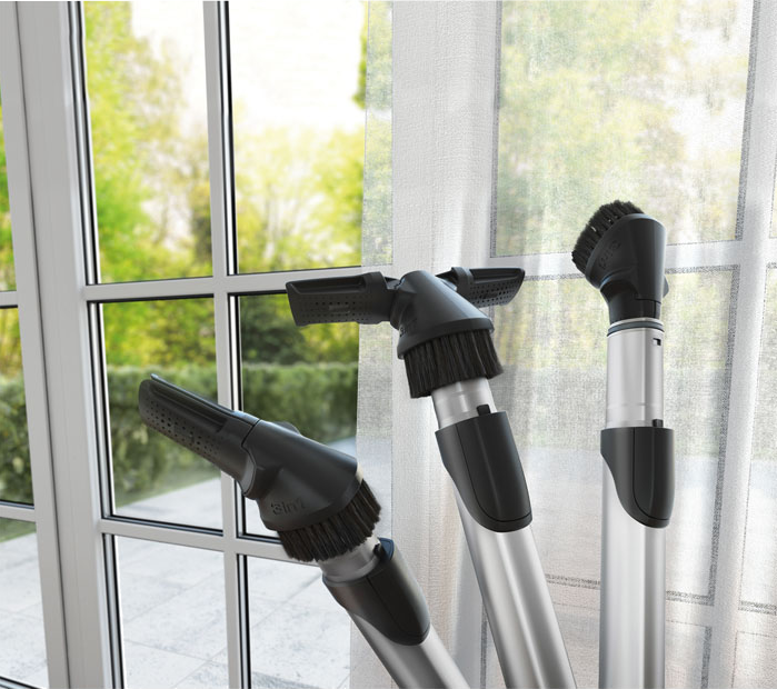 Három porszívófej egy ablak előtt, homályos háttérrel.