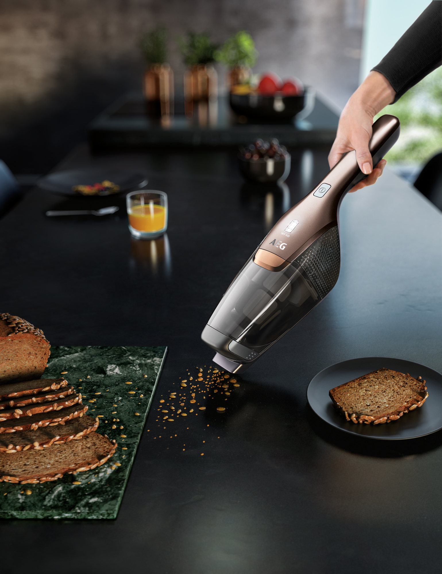 Handstaubsauger reinigt Brotkrumen auf schwarzem Tisch. Brot und Saft sind sichtbar.