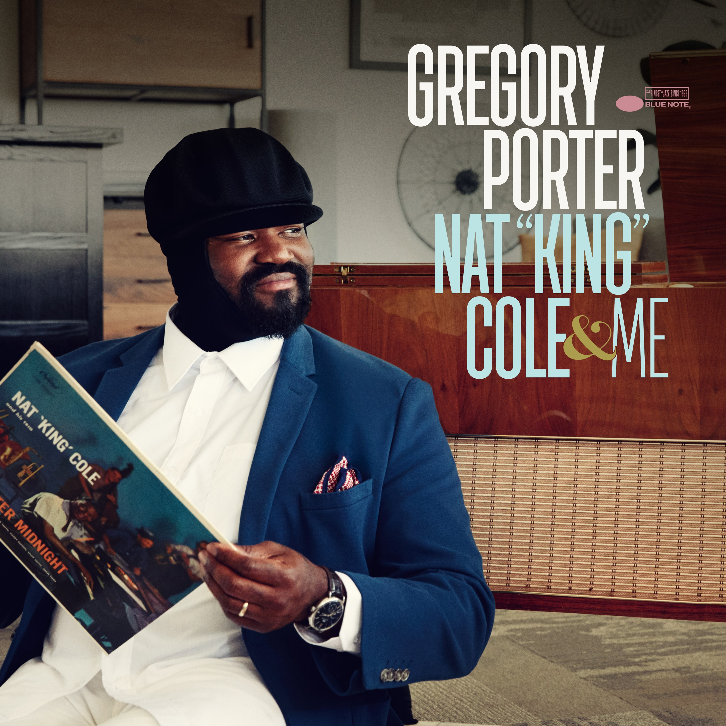 Mann in blauem Anzug hält Schallplatte. Albumcover zeigt Foto von Nat King Cole.