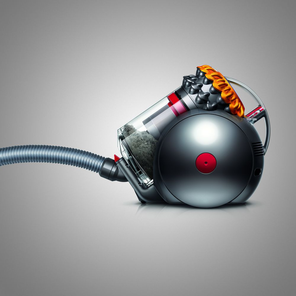 Un aspirateur Dyson, corps gris, réservoir à poussière transparent et un tuyau flexible.