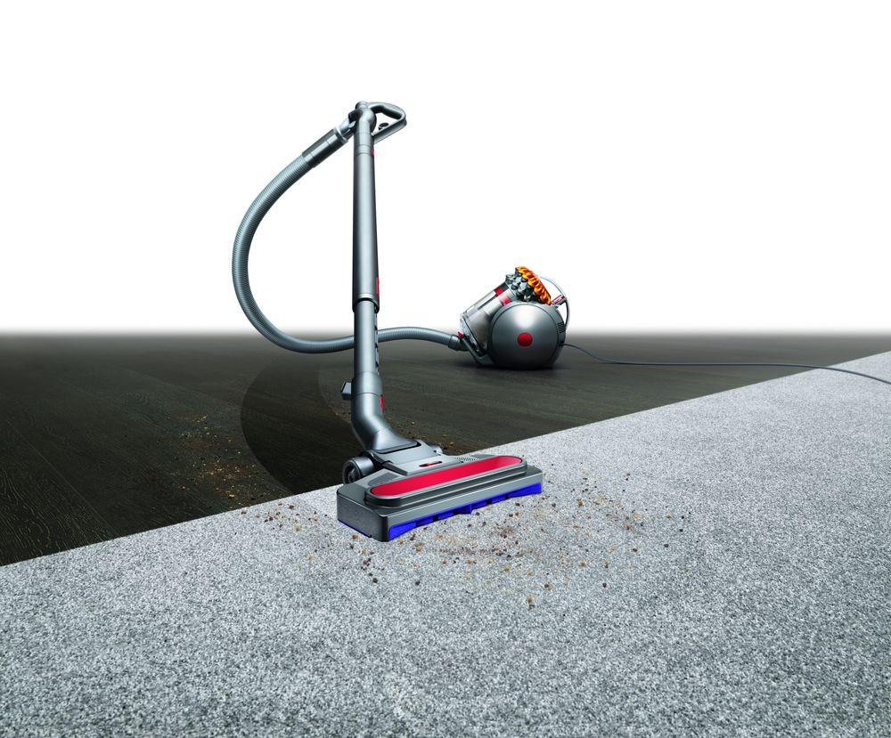 Aspirateur nettoyant un tapis. Une moitié est propre, l'autre a des débris.