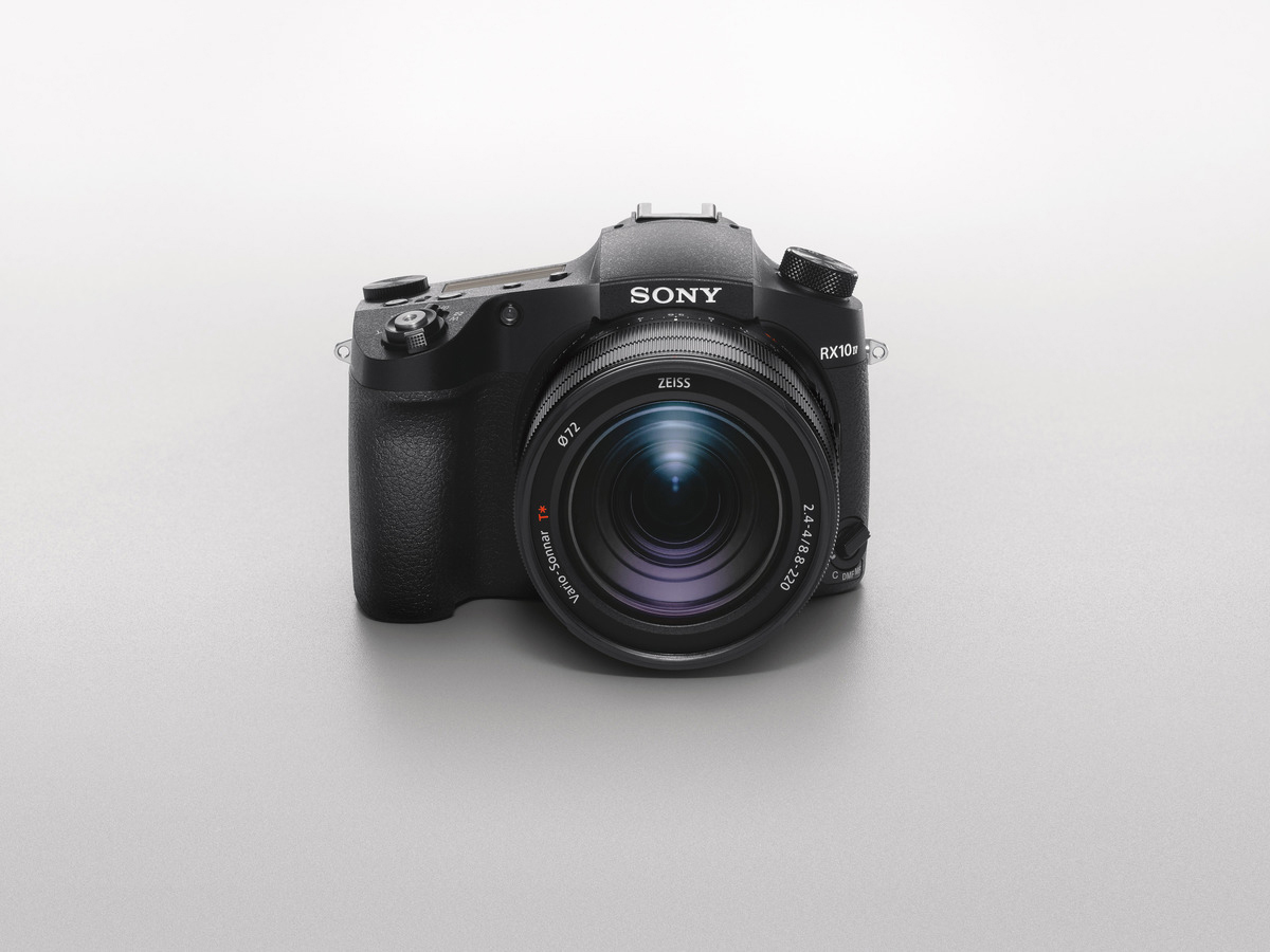 Una fotocamera Sony nera con obiettivo su una superficie grigio chiaro.