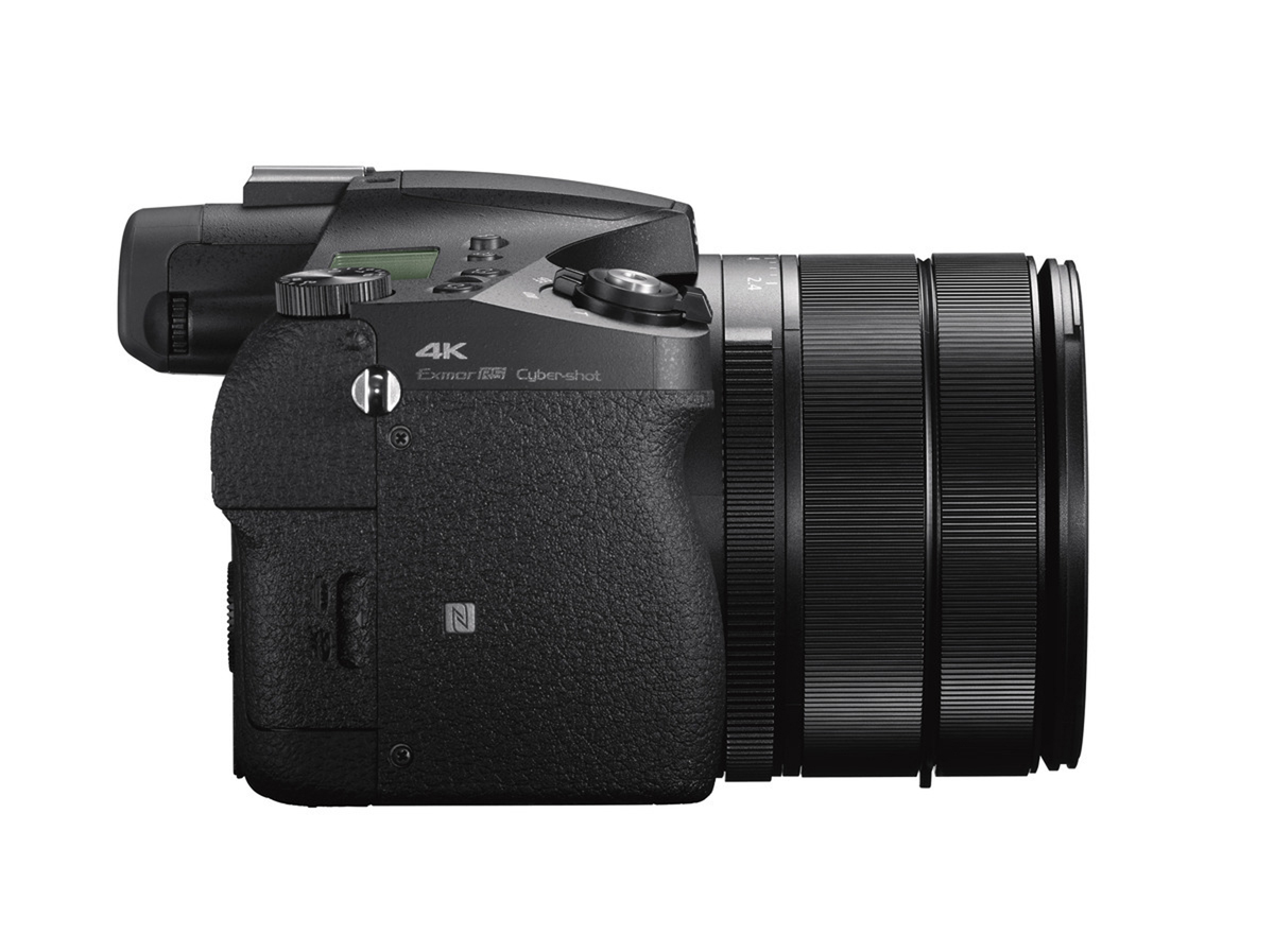 Fotocamera nera con un grande obiettivo, vista laterale, isolata su bianco.