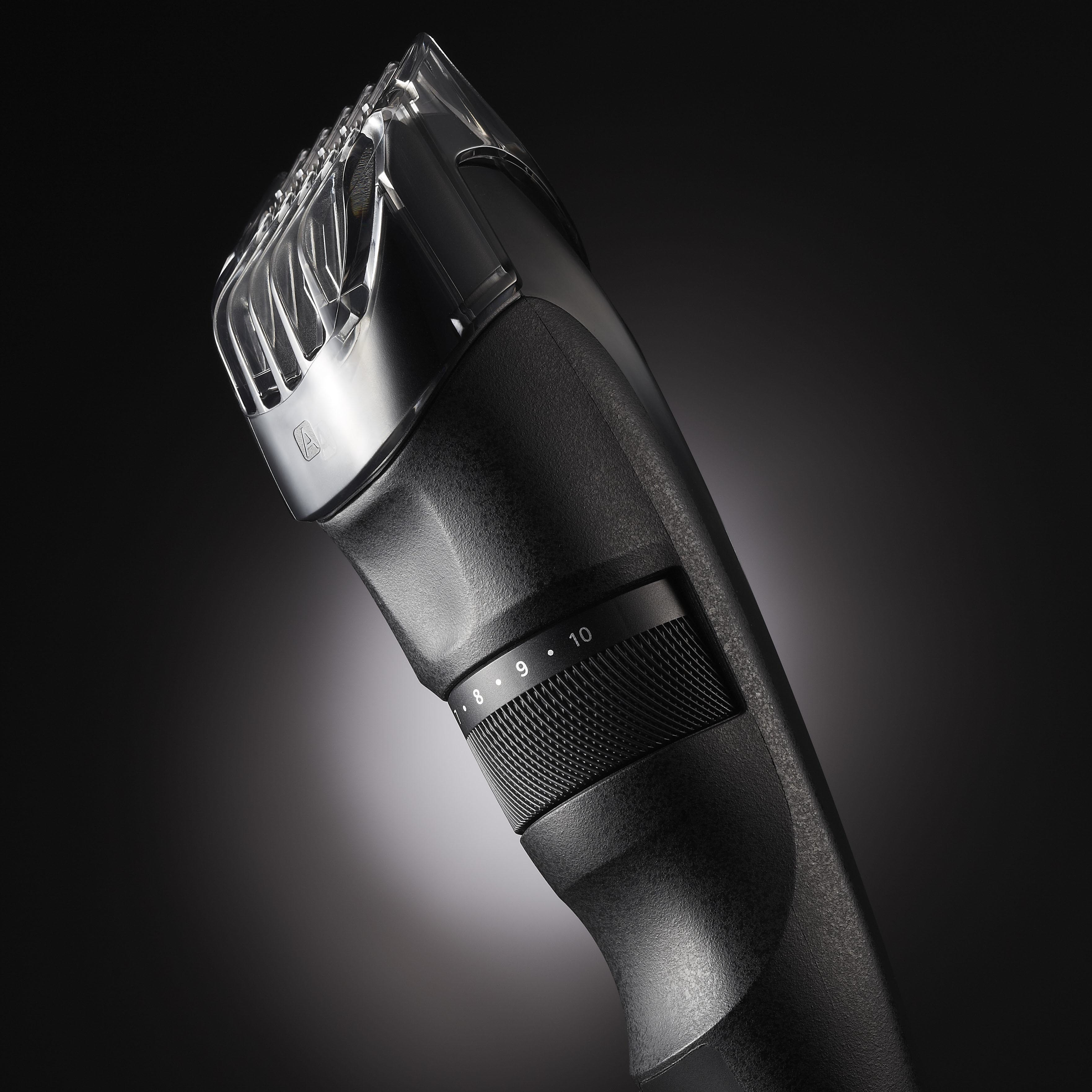 Tondeuse à cheveux noire avec protège-lame en plastique transparent. Chiffres sur le cadran. Fond sombre.
