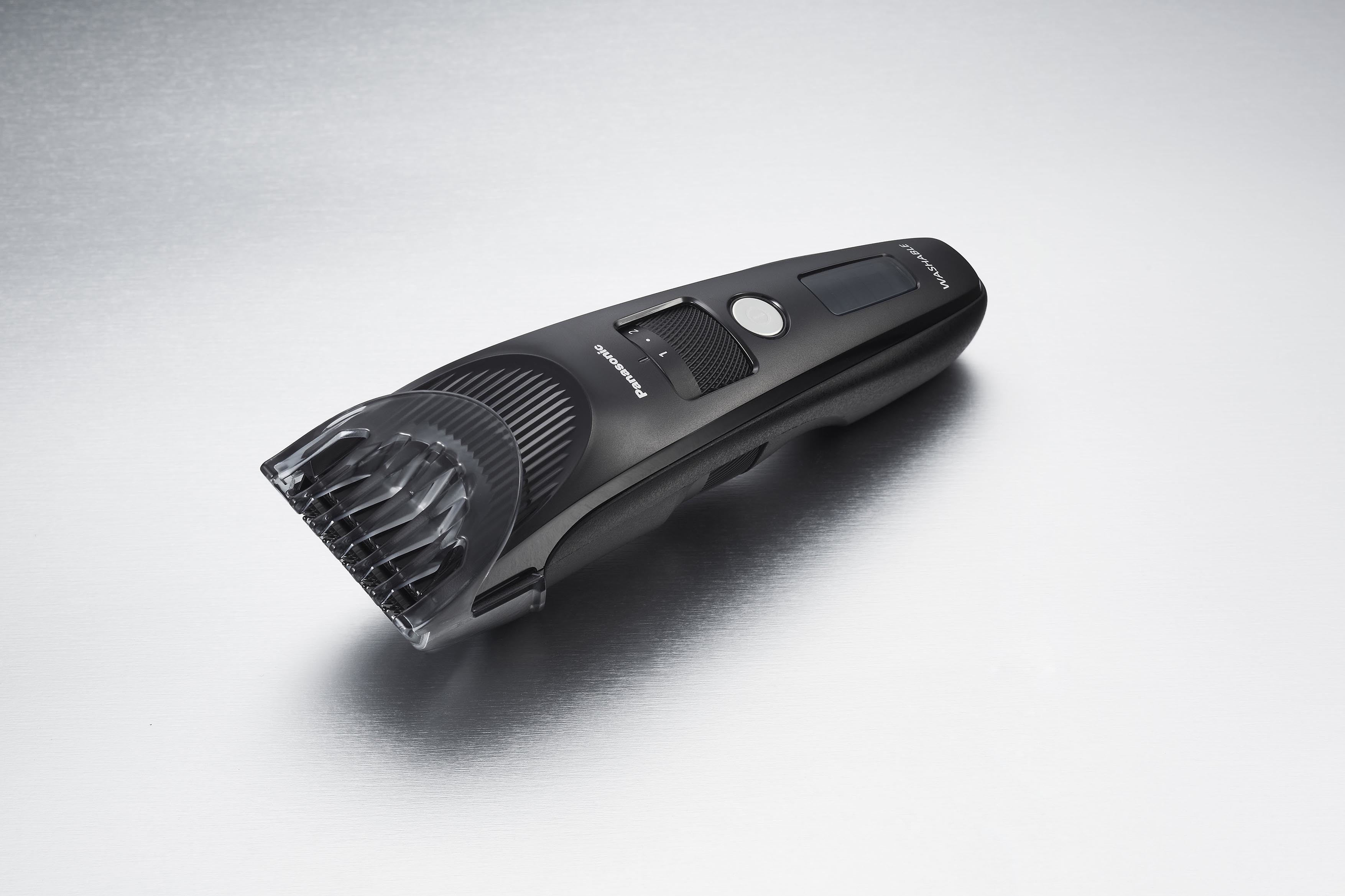 Une tondeuse à cheveux Panasonic noire sur une surface argentée, inclinée vers le spectateur.