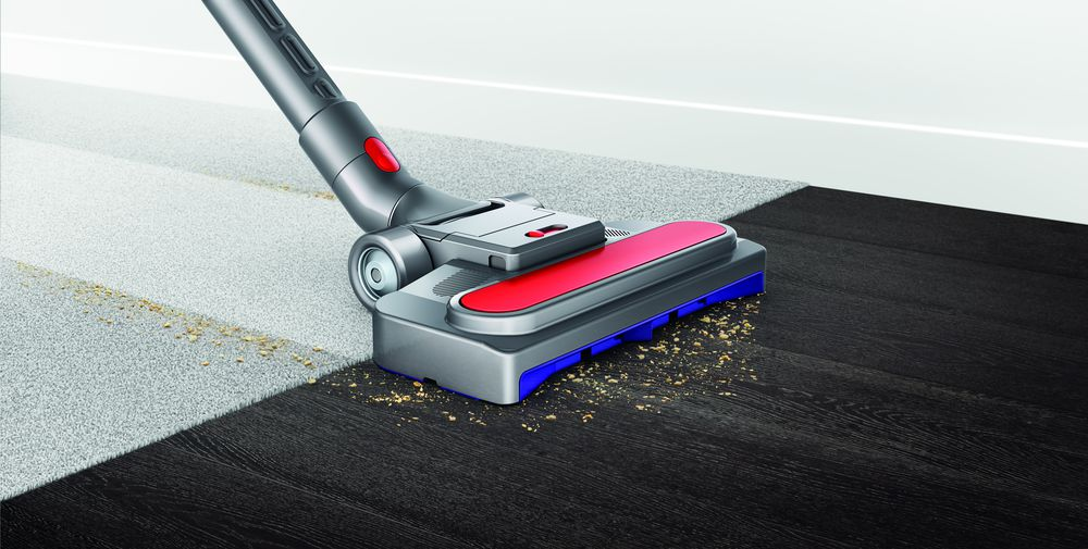 Een Dyson stofzuigerkop maakt een tapijt schoon. Vuil is zichtbaar.
