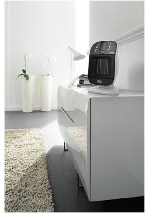 Modern black and white heater on a white cabinet near a rug and plants.