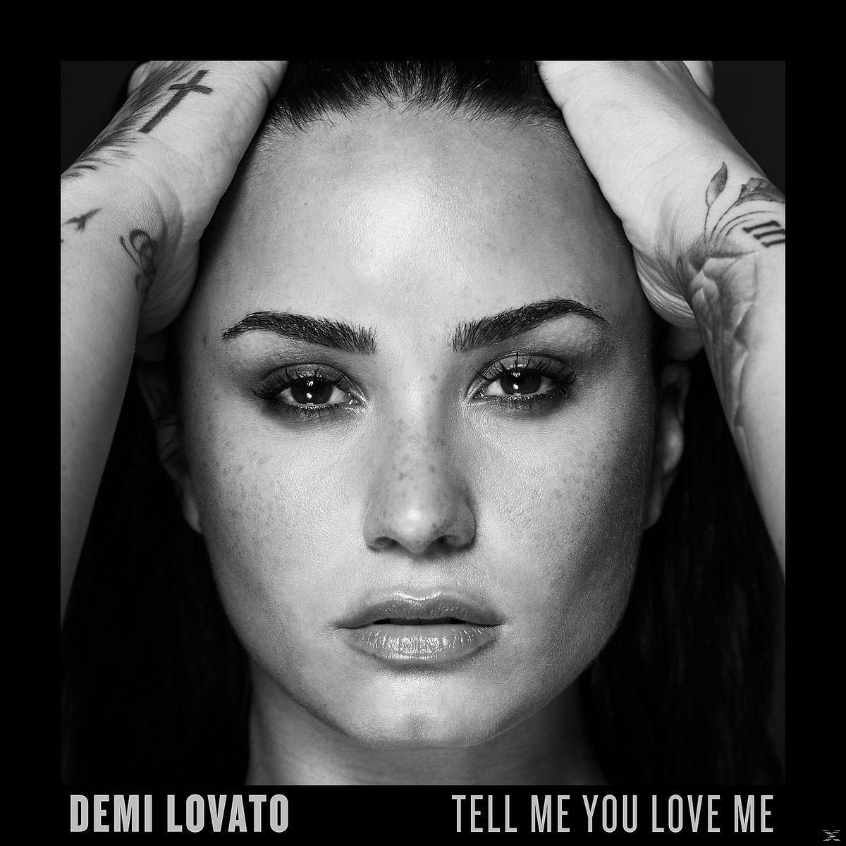 Zwart-witfoto van Demi Lovato, tekst luidt DEMI LOVATO, TELL ME YOU LOVE ME.