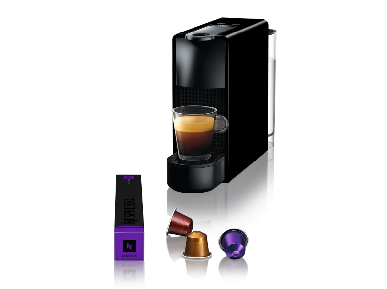 Egy fekete Nespresso gép egy csésze kávéval és kapszulákkal.