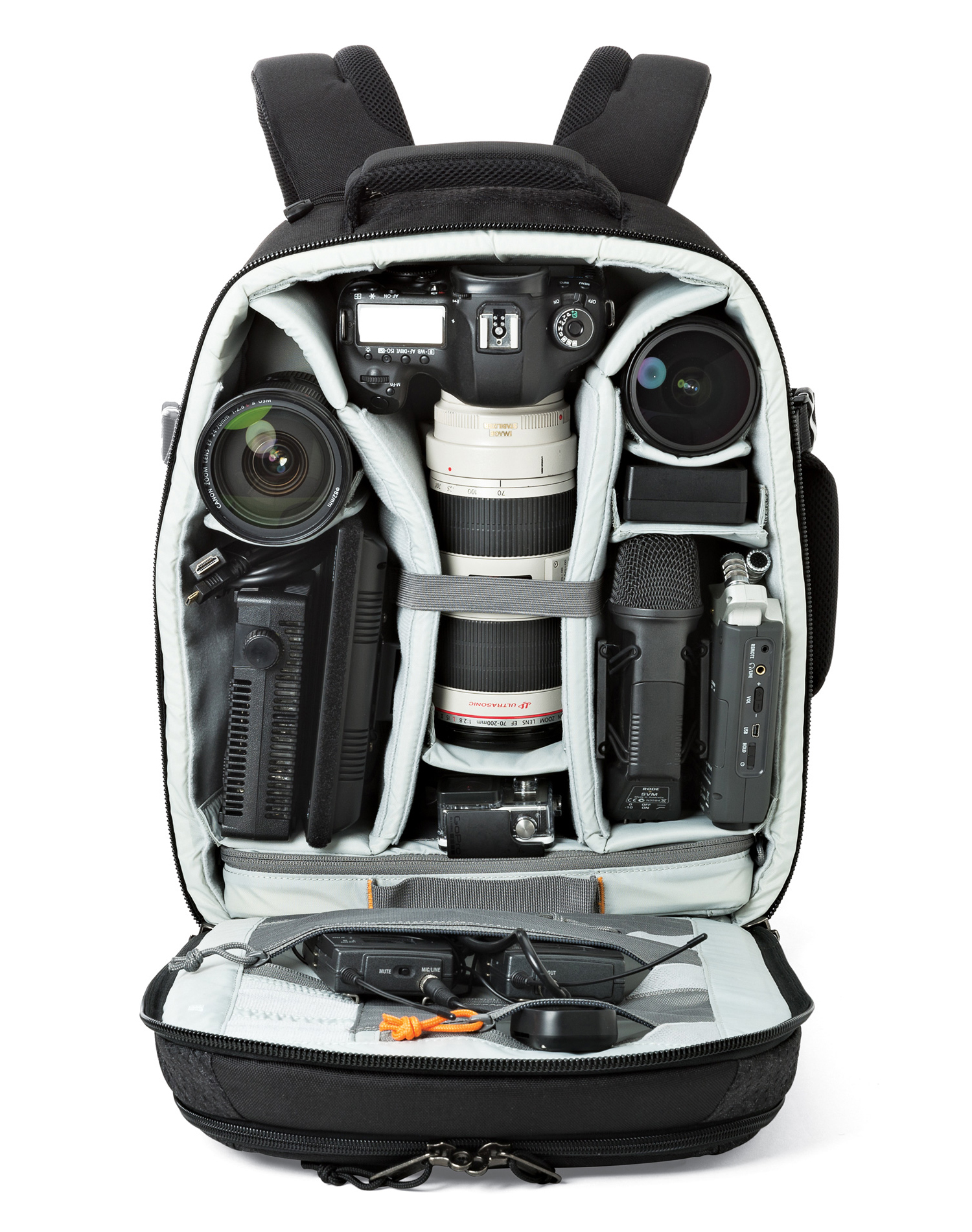 Black camera backpack open, filled with camera equipment: camera, lenses, microphone, and accessories. Isolated on white background.