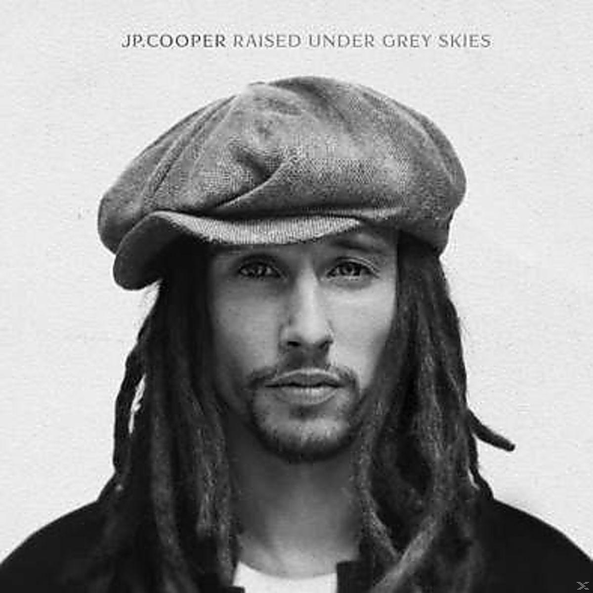 Gros plan en noir et blanc d'un homme avec des dreadlocks et une casquette.