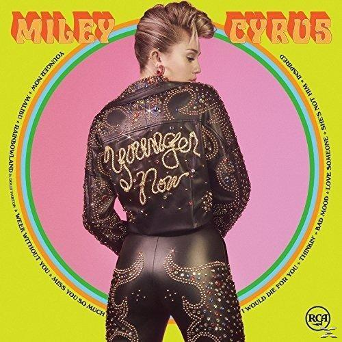 Miley Cyrus Albumcover. Sie trägt eine Jacke und Hose aus Leder mit Nieten. Der Hintergrund ist pink und grün mit Songtiteln.
