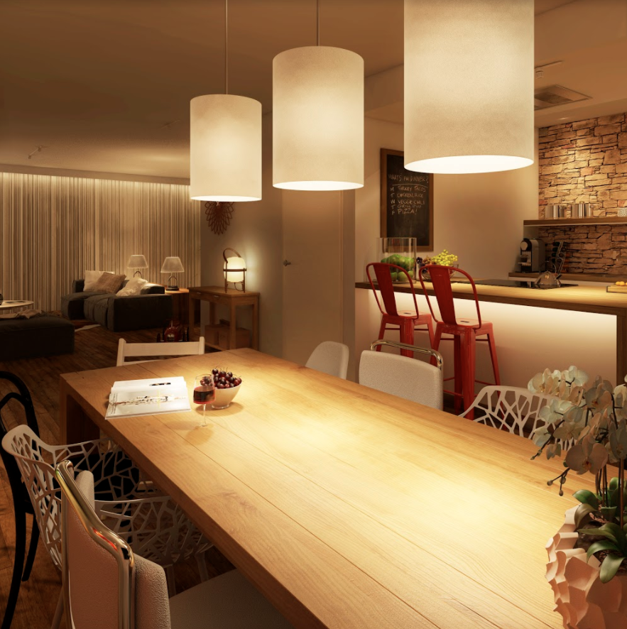 Een interieur eetgedeelte met een lange houten tafel, hanglampen en een keuken achterin.
