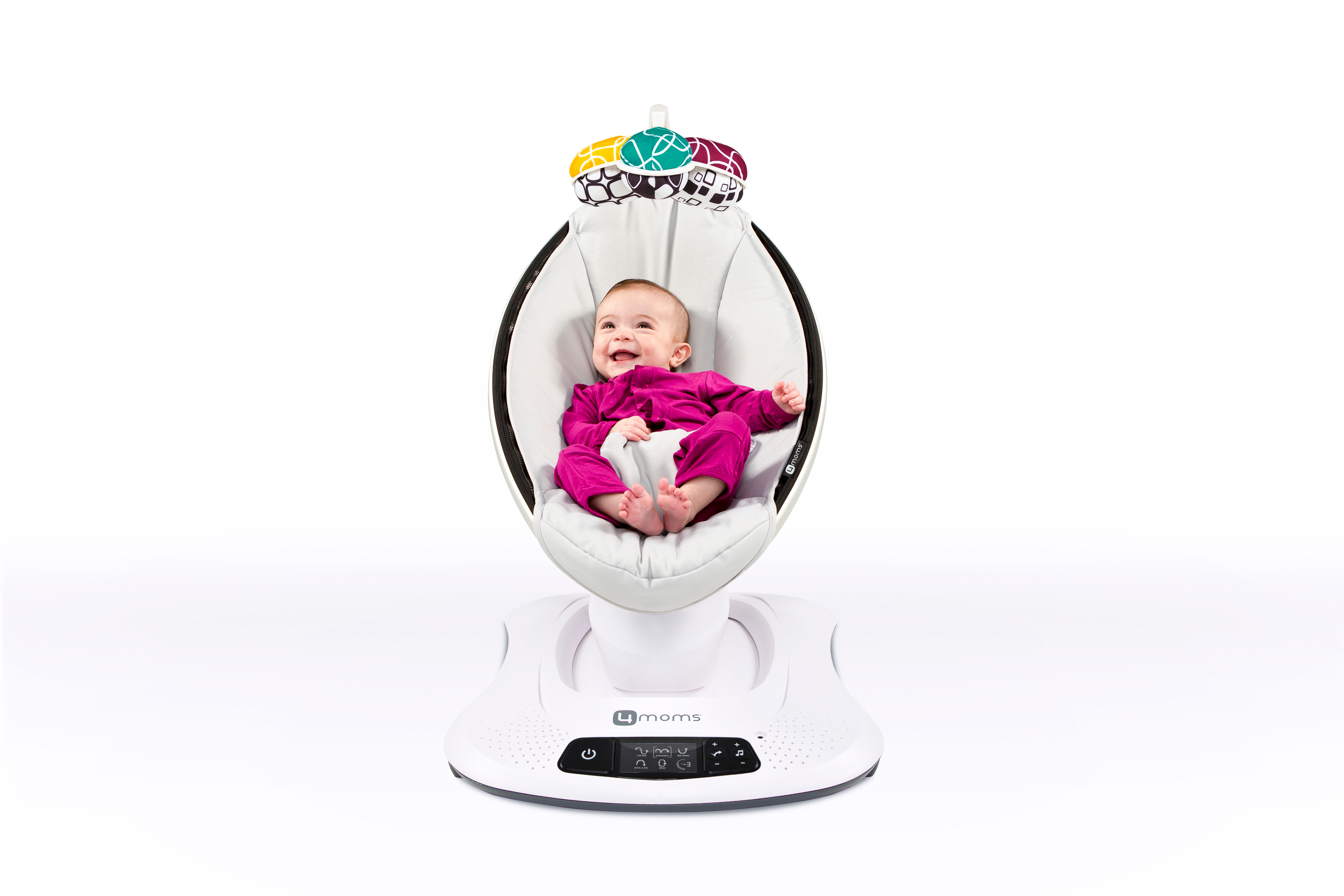 Ein Baby in rosa Kleidung sitzt in einer weißen Schaukel und lächelt. Weißer Hintergrund.